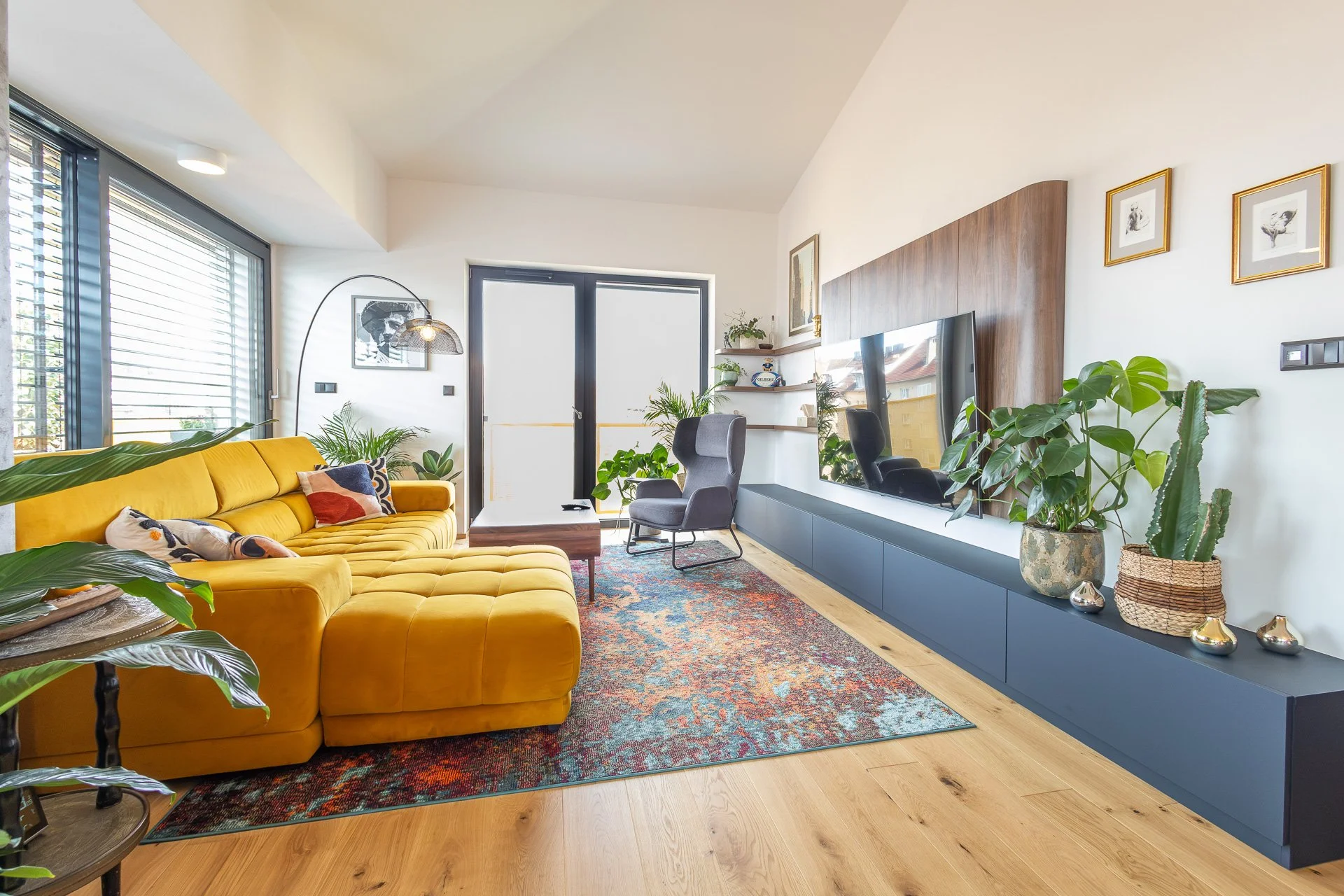 Náhled na celý obývací pokoj s květinami a dřevěným obkladem (penthouse Šrámkovka, České Budějovice)