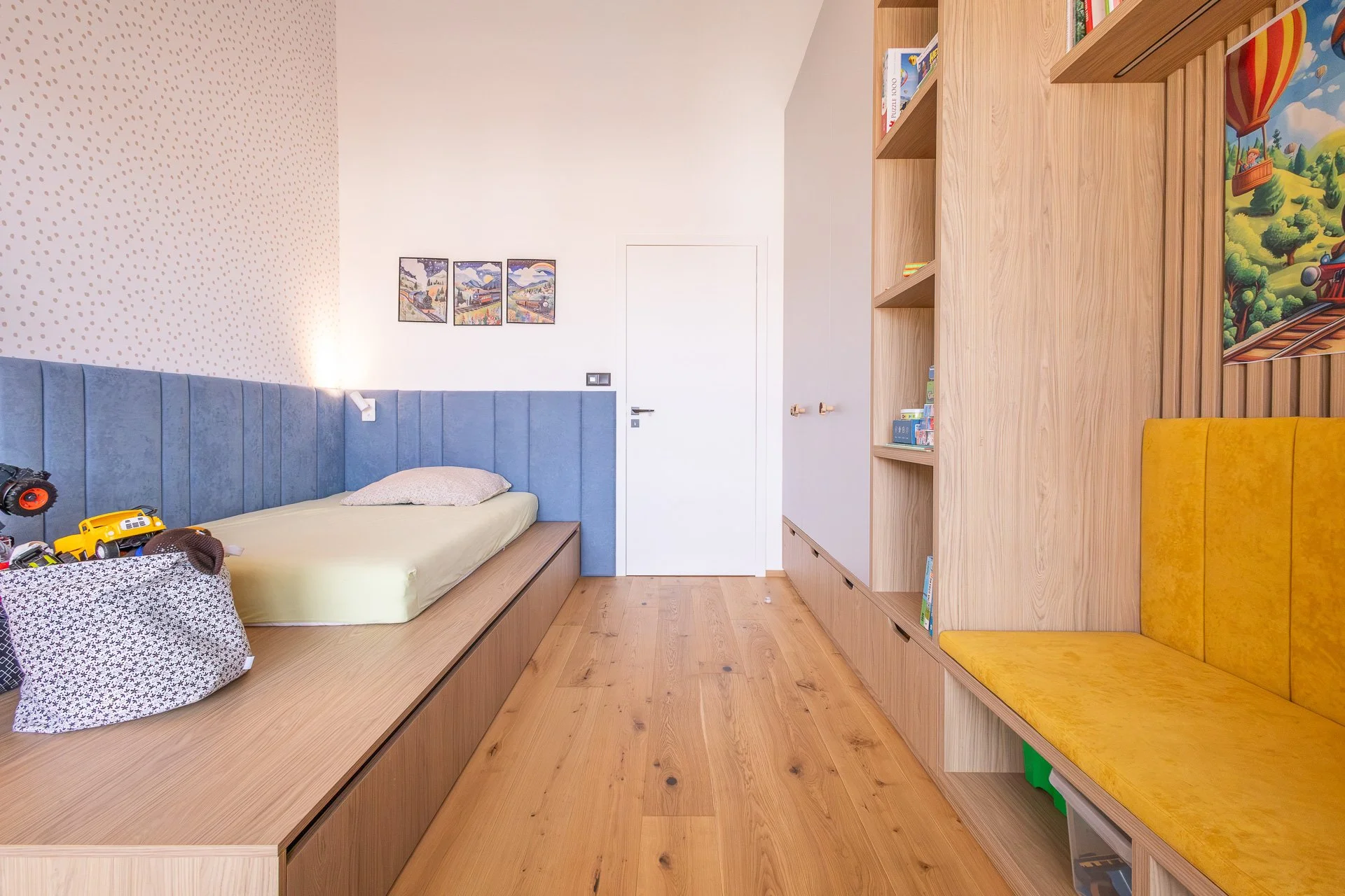 Chlapecký pokoj s postelí na dubovém pódiu a modrými čalouněnými panely (penthouse Šrámkovka, České Budějovice)