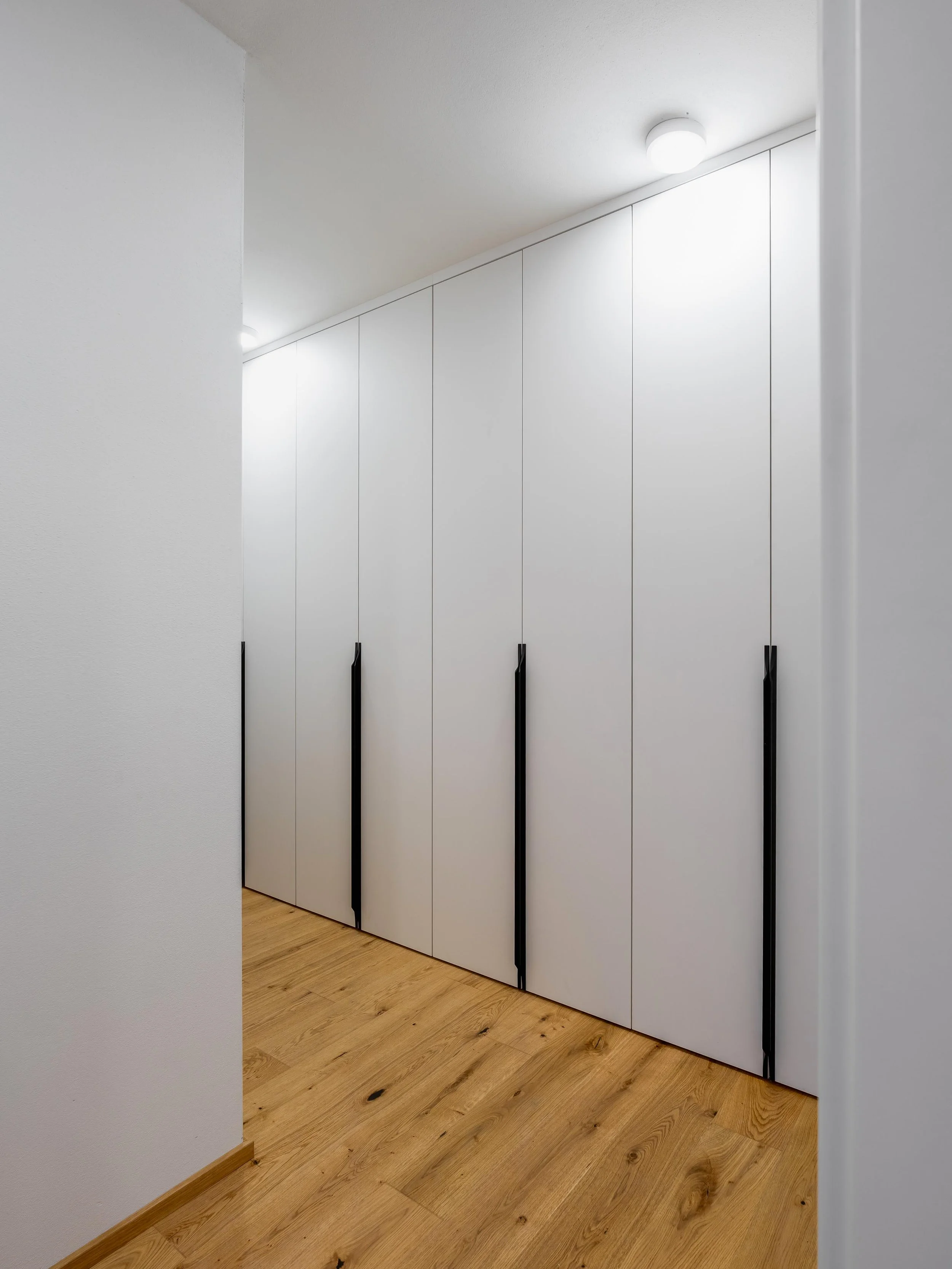 Elegantní vestavěné skříně v předsíni bytu 4KK s bílou a šedou laminátovou povrchovou úpravou