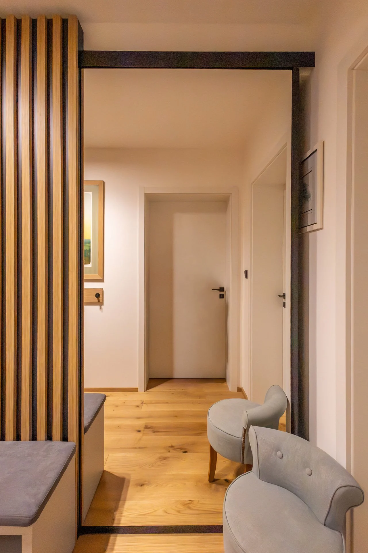Lavice se šedým sedákem a posuvné zrcadlové dveře v černém rámu (penthouse Šrámkovka, České Budějovice)
