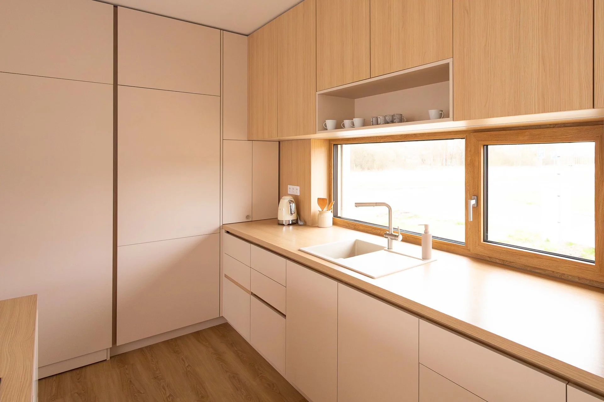 Kuchyňská pracovní deska s dřezem pod oknem a horními dubovými skříňkami s LED podsvícením - RD Hluboká nad Vltavou