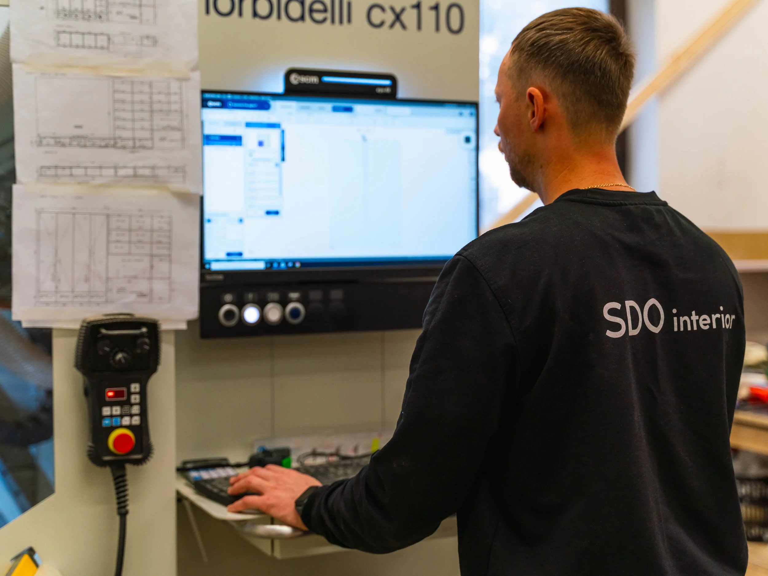 Technik konfiguruje CNC stroj v dílně, zajištění digitální přesnosti výroby nábytku, moderní technologie.