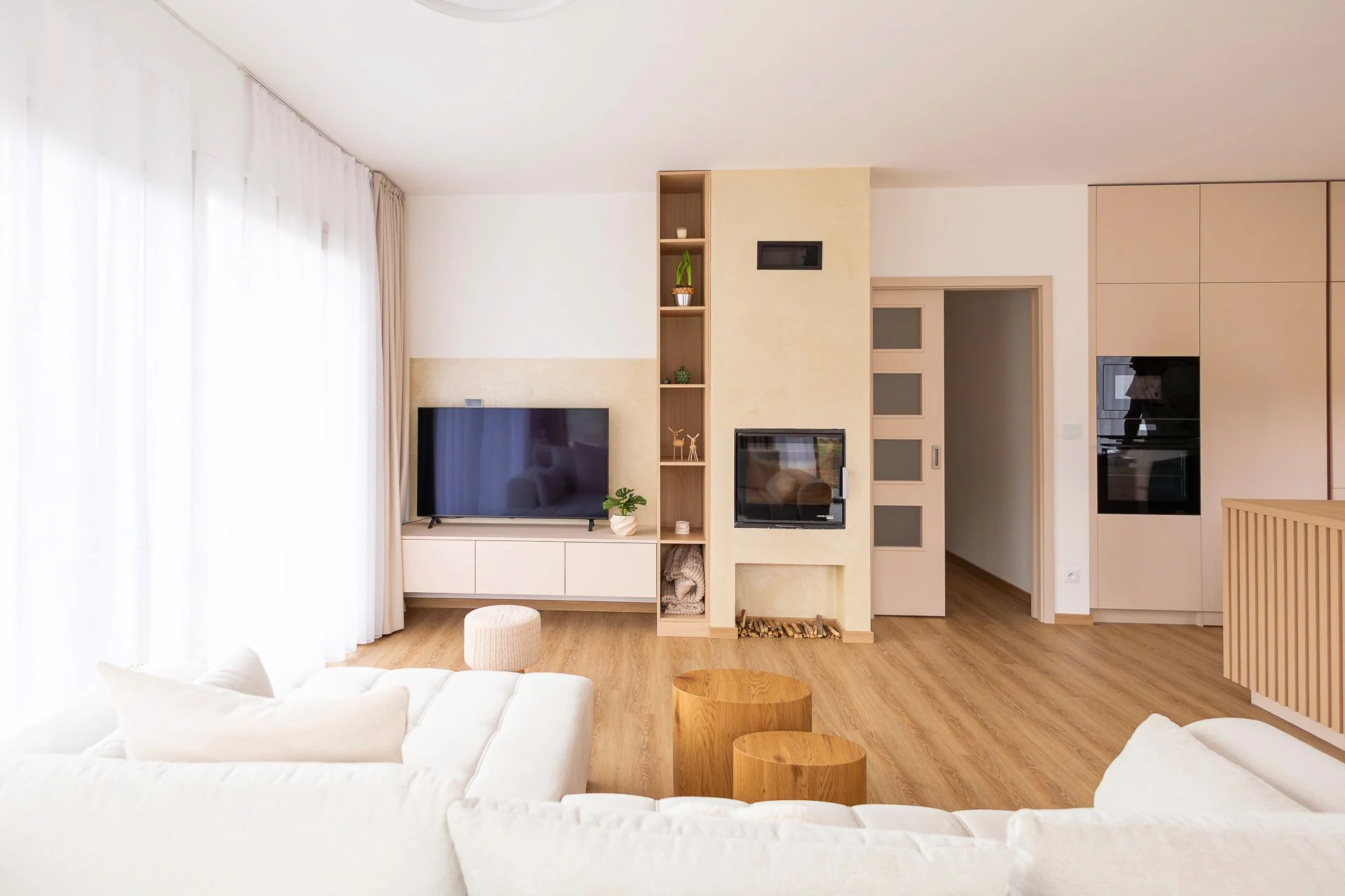 Pohled od kuchyňského ostrůvku s lamelovým dubovým frontem do obývacího pokoje se sedačkou - RD Hluboká nad Vltavou