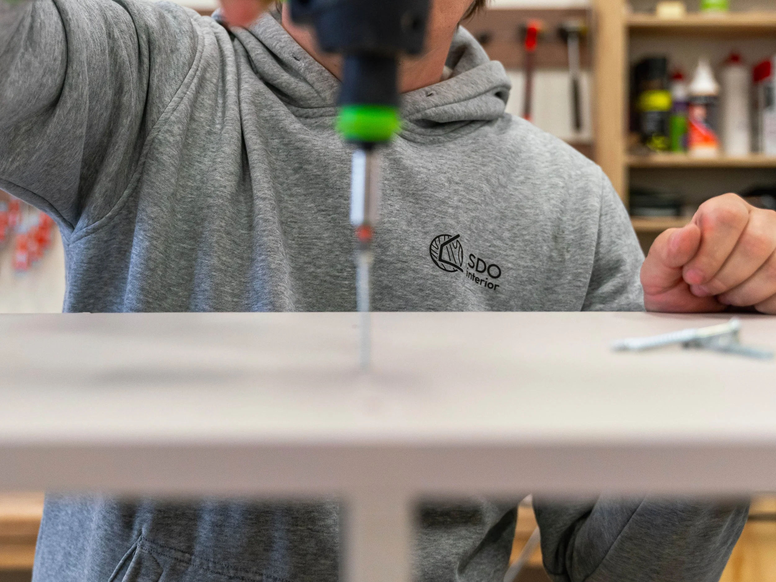 Alt text: Detailní záběr na truhláře montujícího nábytek na míru, šroubování, kontrola kvality, precizní řemeslná práce.