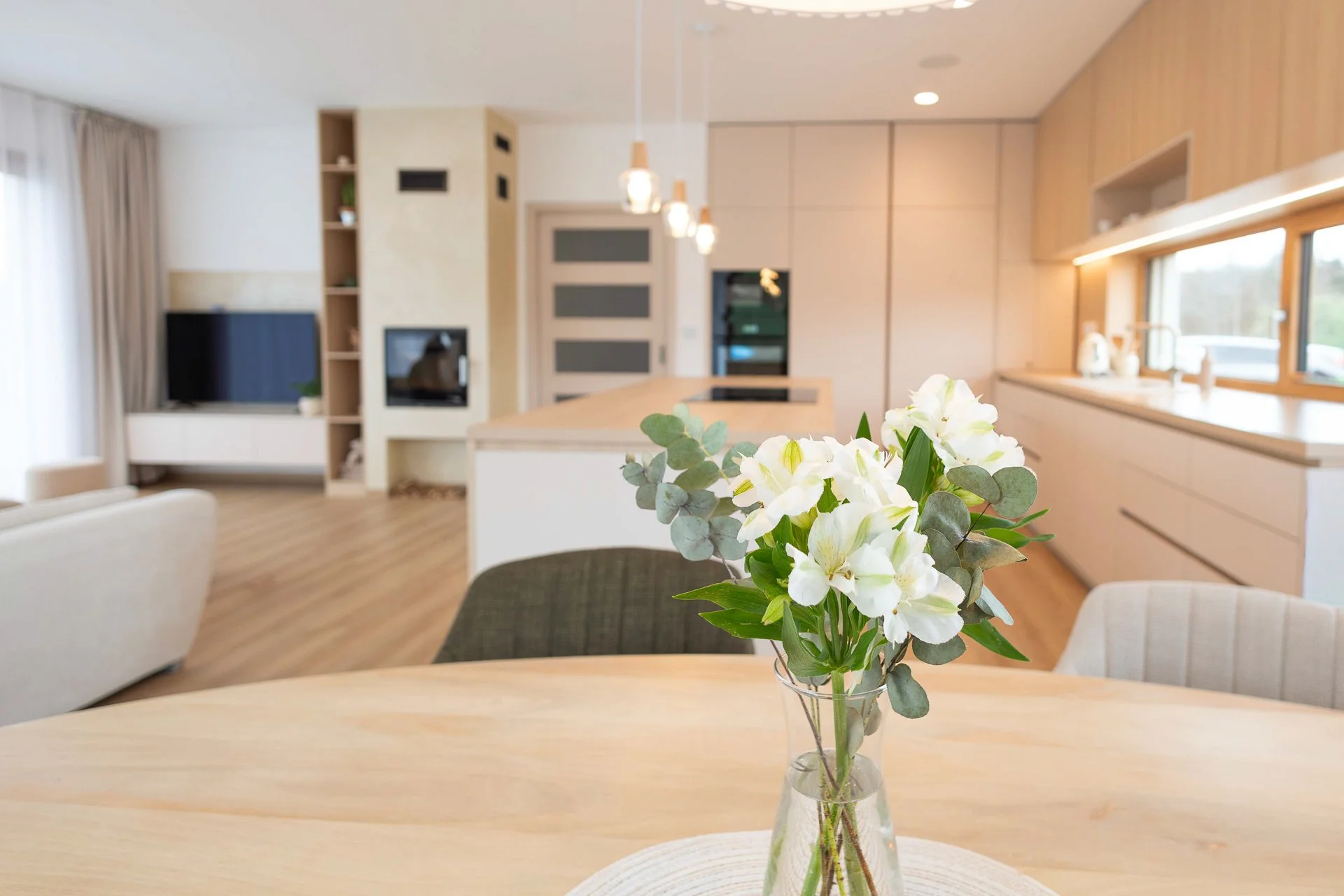 Celkový pohled na obývací pokoj s TV stěnou, krbem, otevřenými policemi a napojením na kuchyni - RD Hluboká nad Vltavou