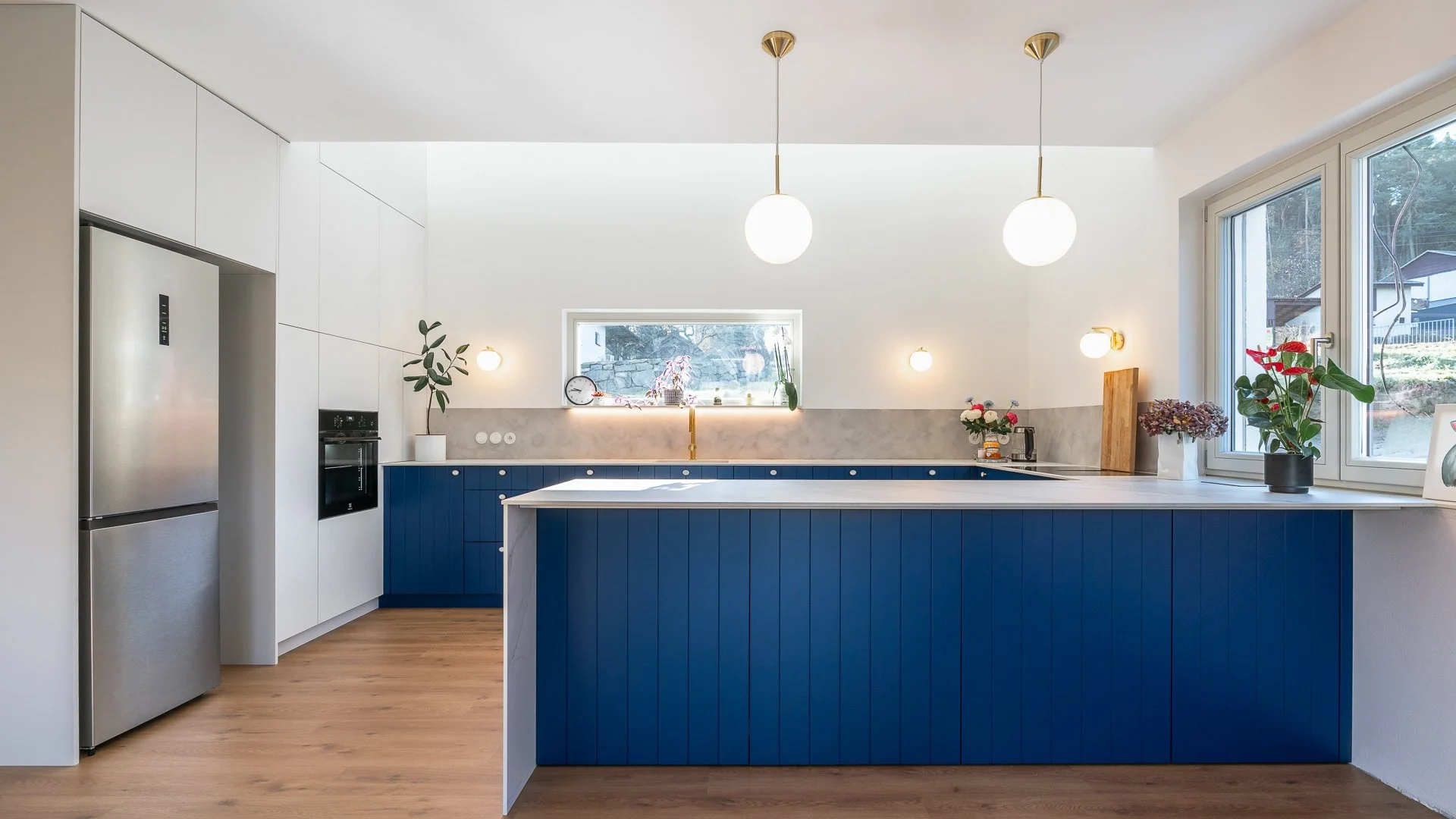 Moderní kuchyně s modrými skříňkami a zlatými úchytkami, elegantní design, bílá pracovní deska