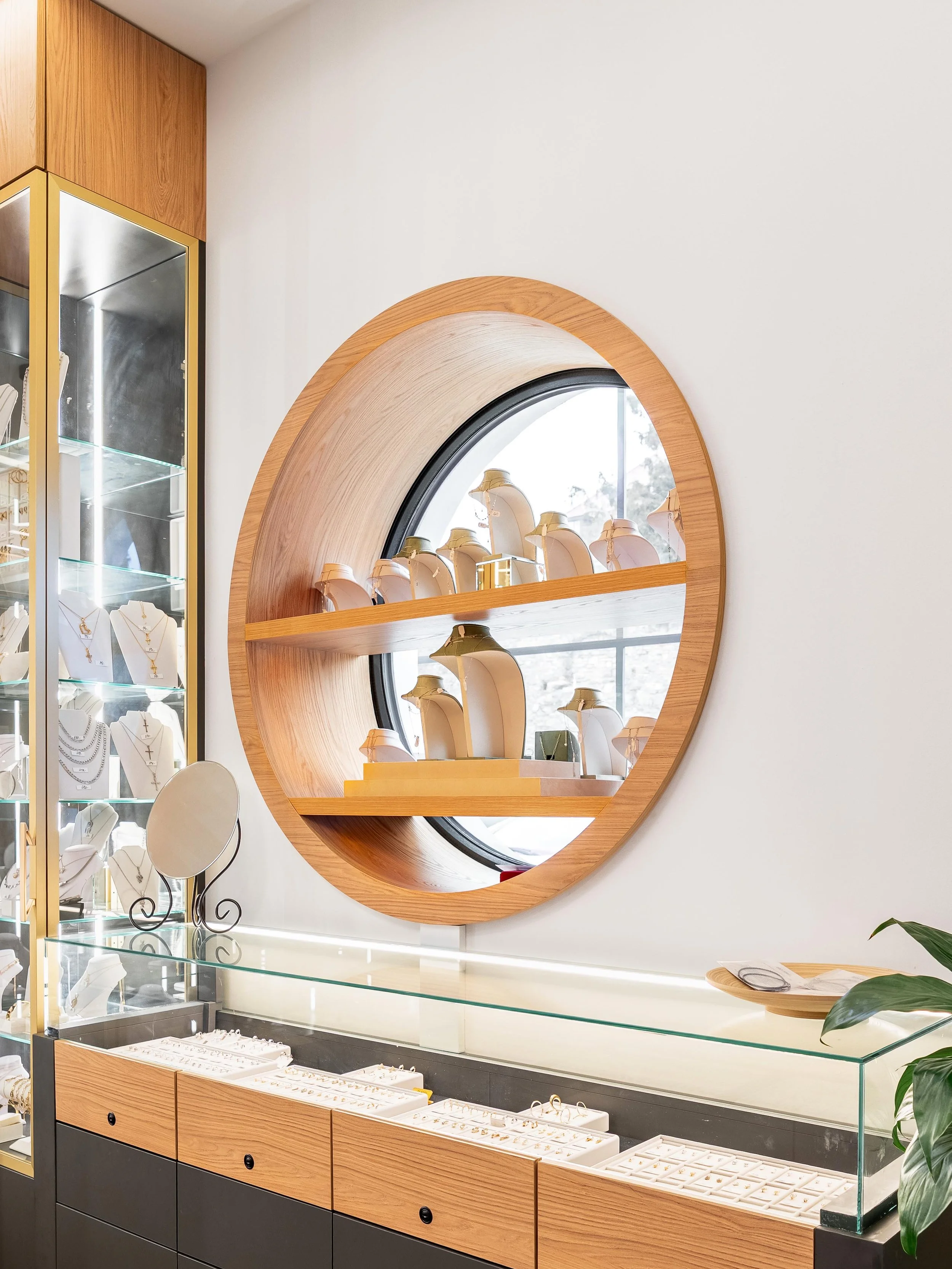 Detail kulaté výlohy s vystavenými šperky a minimalistickým pozadím