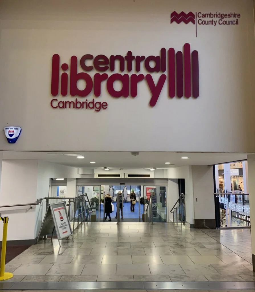 Entrance to Cambridge Central Library with signage and people entering.