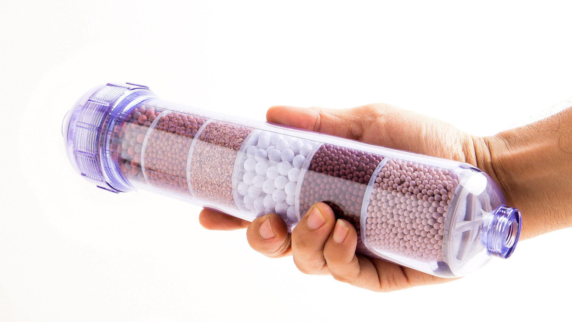 A hand holding a cylindrical container with compartments filled with different colored and sized beads.