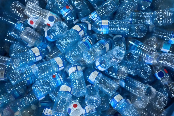 Pile of discarded small plastic water bottles with blue labels.