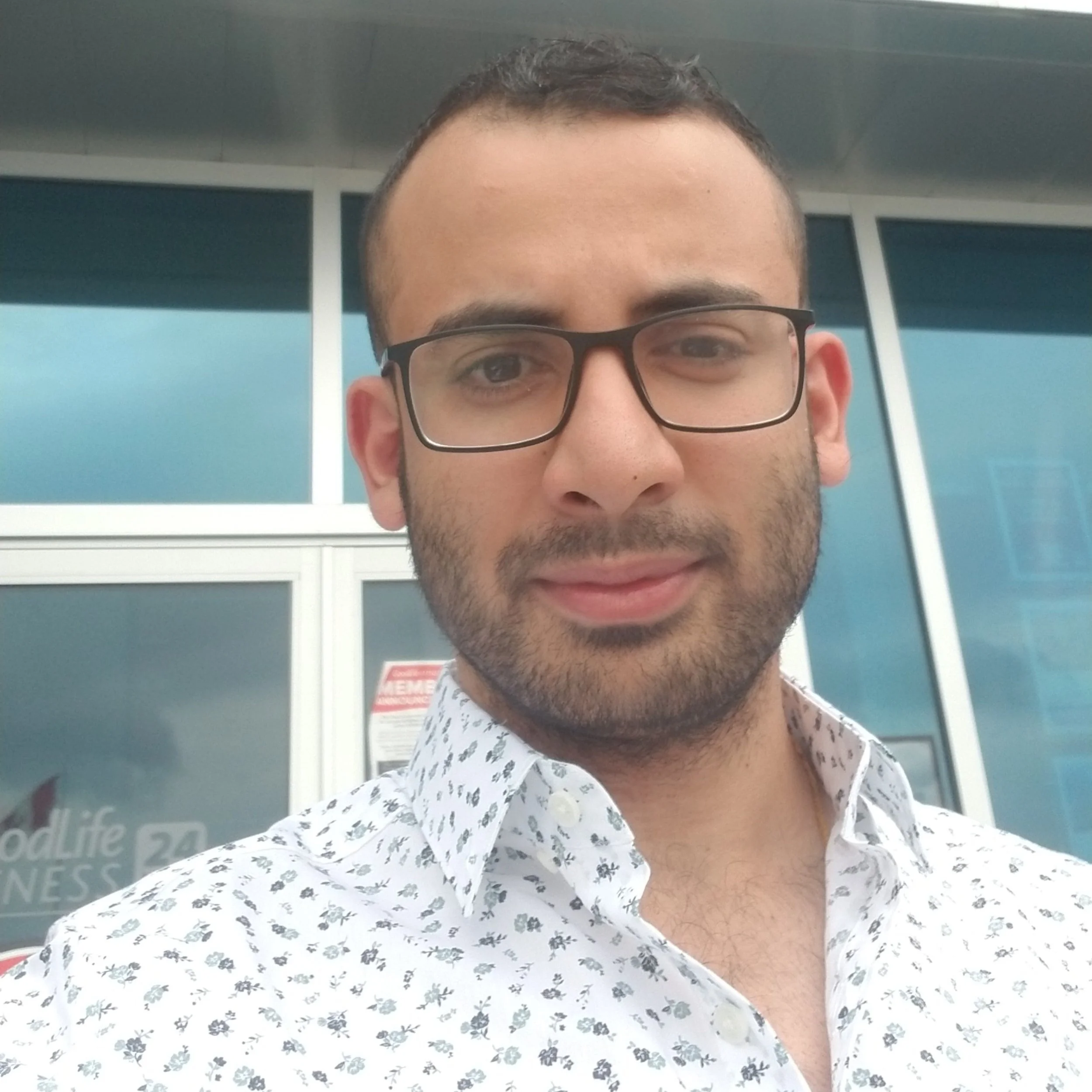 Ishan Verma, personal trainer, wearing glasses and a white patterned shirt.
