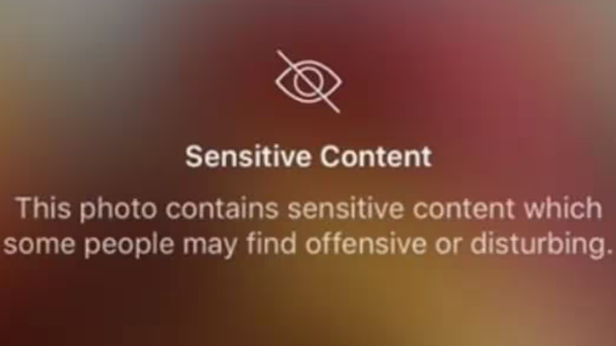 This image shows how instagram marks images it considers to be offensive or disturbing. It includes an icon of an eye with a line through it, a blurry red and orange background, and a content warning.