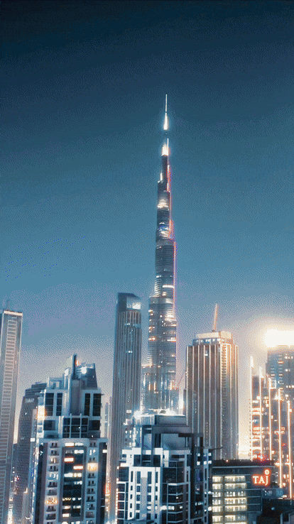Nighttime view of Dubai skyline with Burj Khalifa, the world's tallest building, illuminated and towering over surrounding skyscrapers.