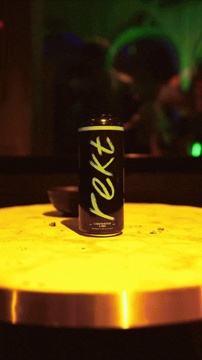 A black can with yellow lettering that says "ret" is on a yellow surface, with a small dark bowl behind it. The background includes a mirror reflecting a green item and blurry figures.