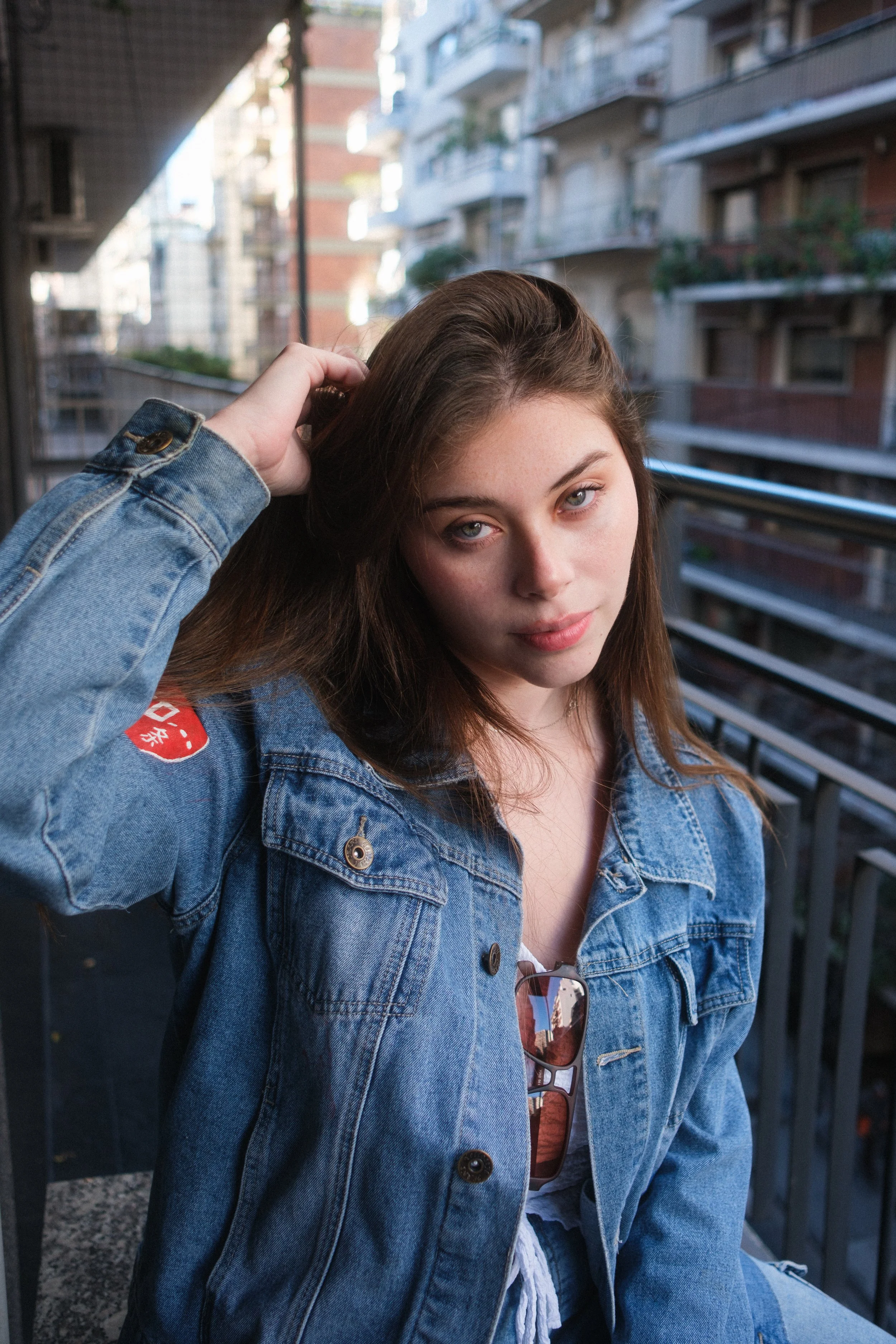 Joven mujer con vestido de mezclilla en un balcón en una zona urbana.