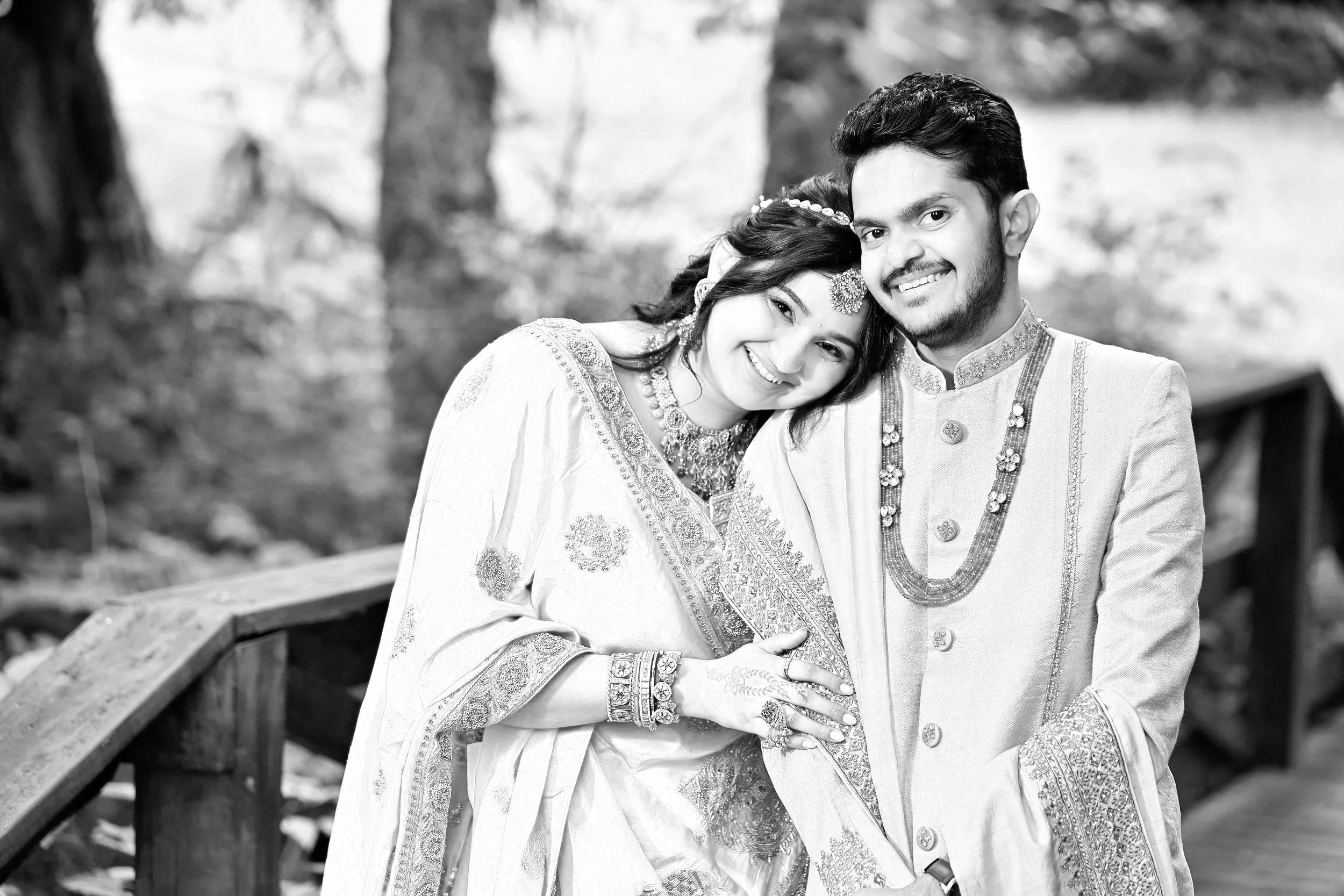 A group of people dressed in traditional Indian attire, standing indoors against a wooden wall.