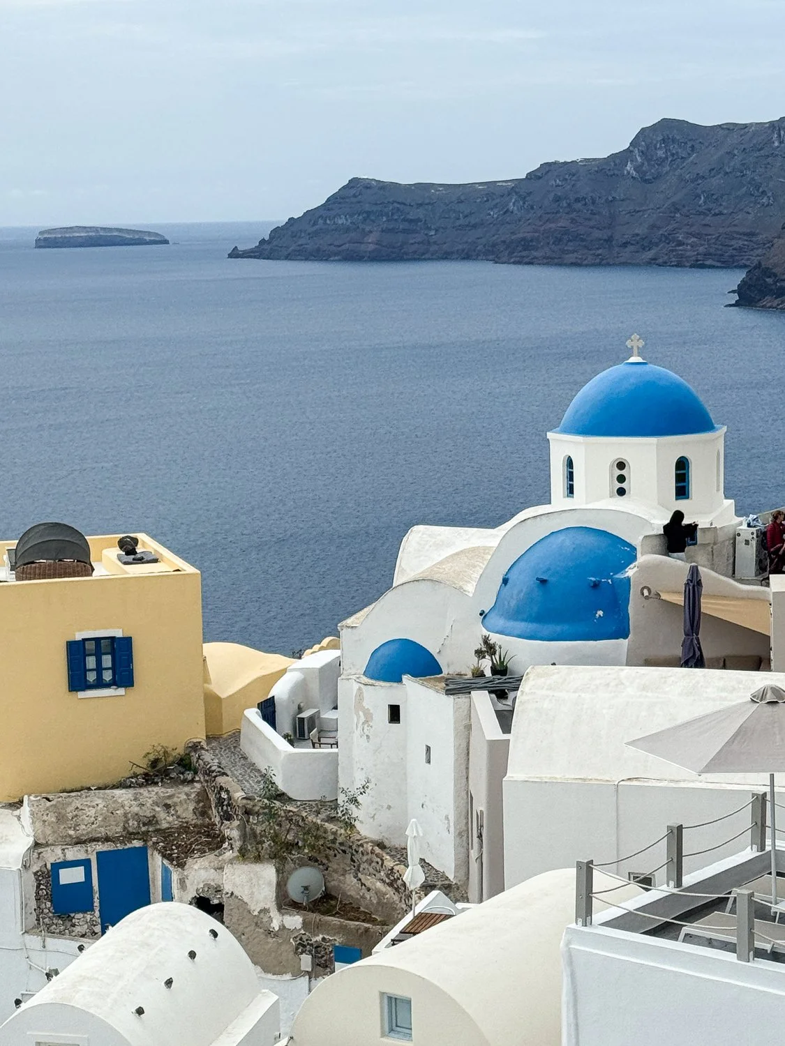 Blue-domed churches and whitewashed buildings in Oia, Santorini, Greece, overlooking the Aegean Sea. 