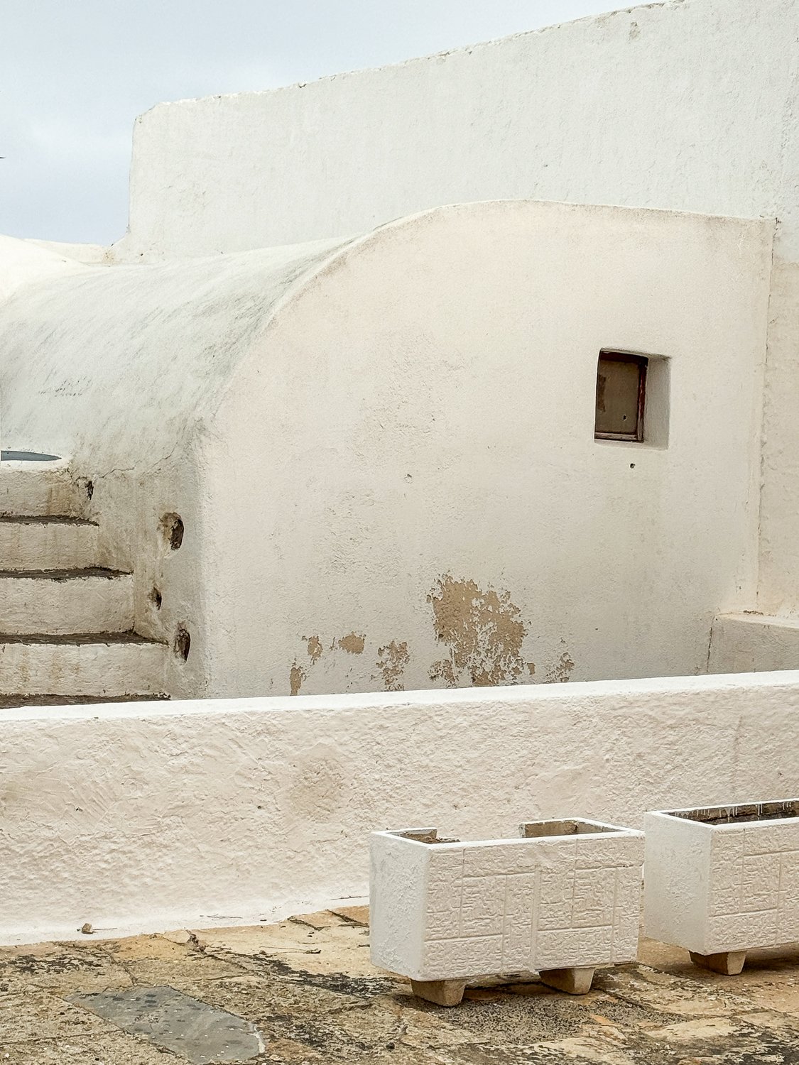  Curved Cycladic architecture with textured white and beige walls in Oia, Santorini, Greece. 