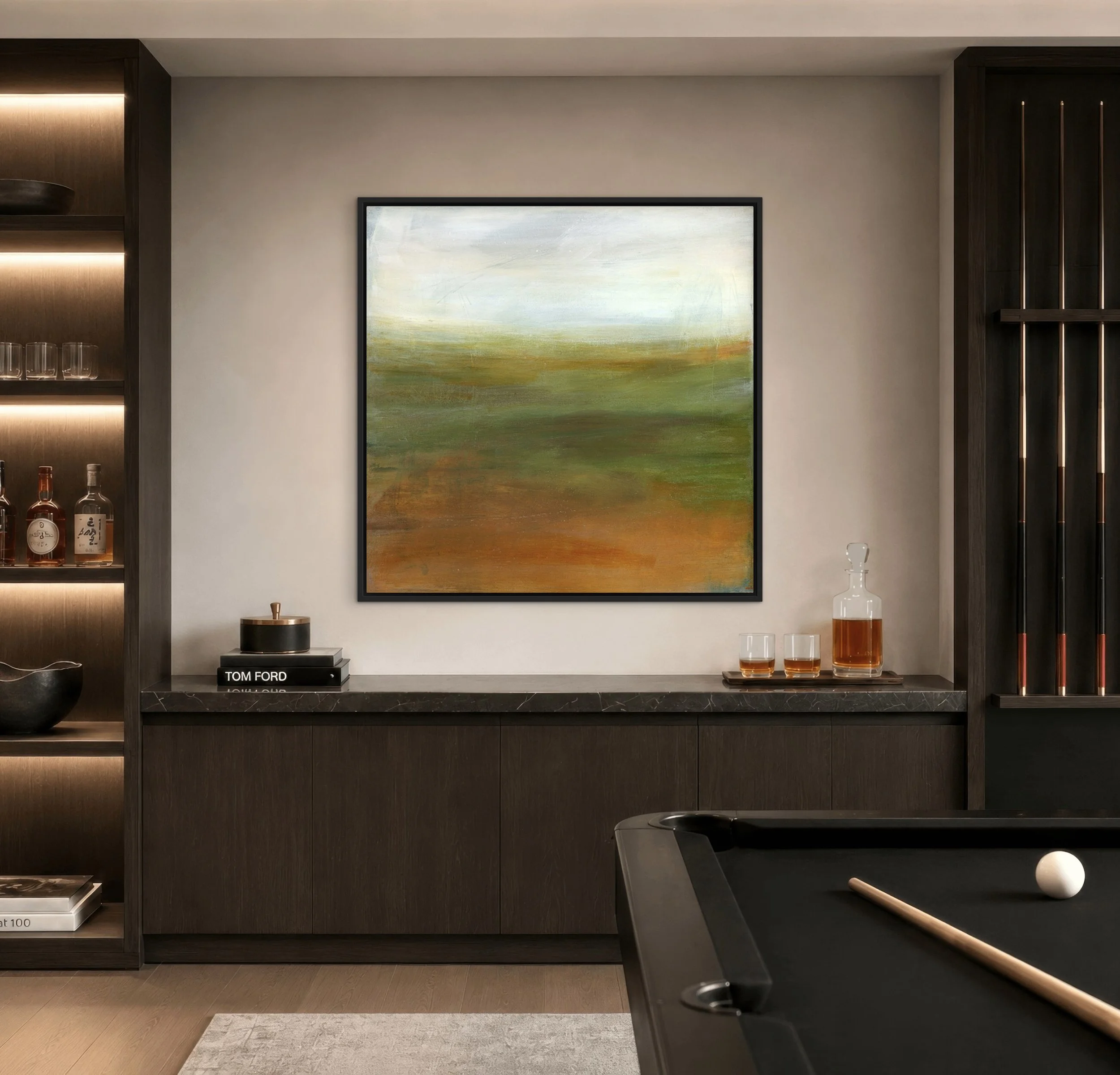 A Quiet Morning abstract landscape art print in green, ochre, and rust tones, framed in black above a dark wood cabinet in a modern game room.