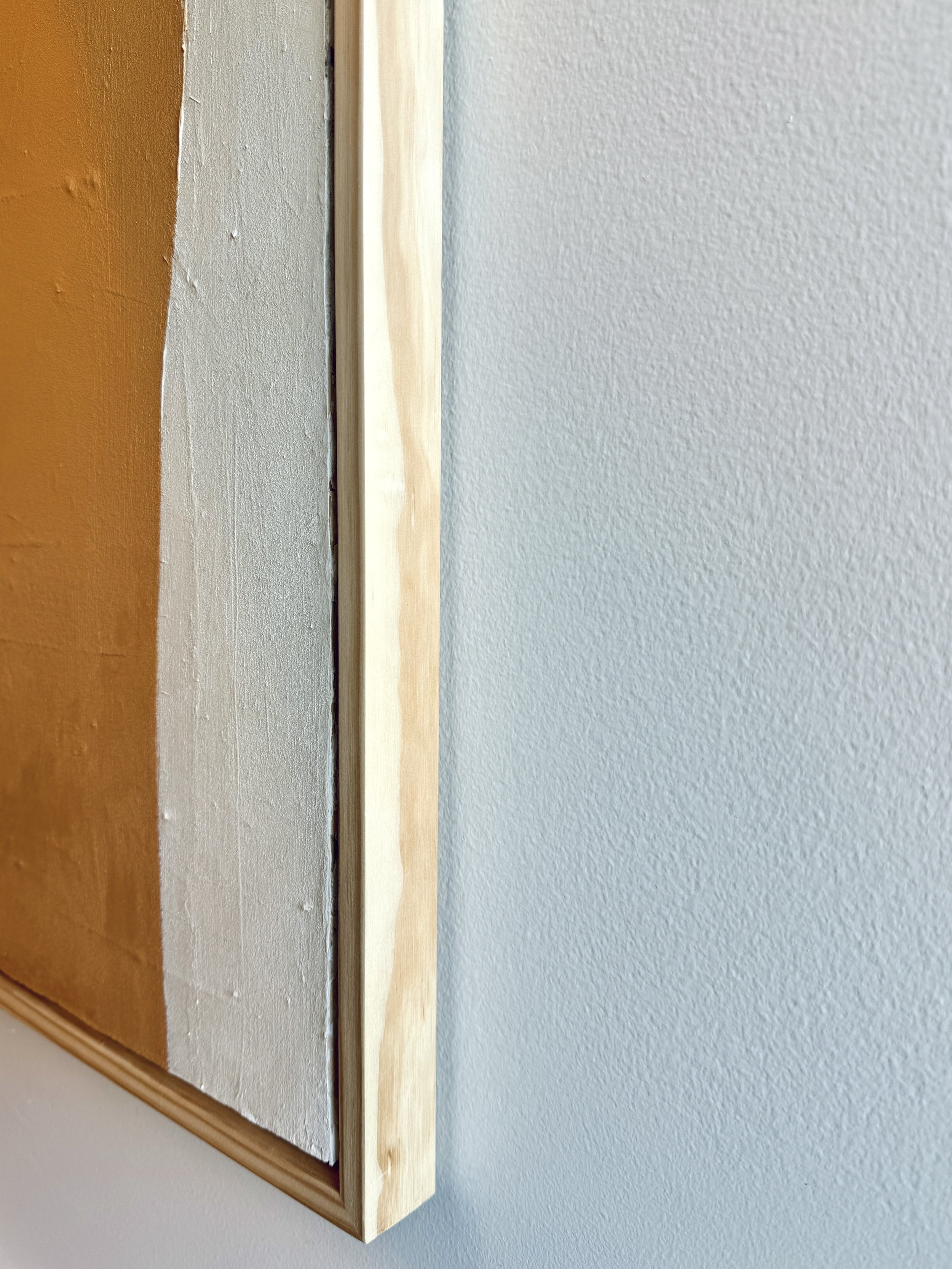 A profile shot of the painting showing its textured surface and natural wood frame.