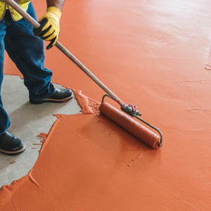 Person using a roller to spread orange-colored paint or coating on a surface.