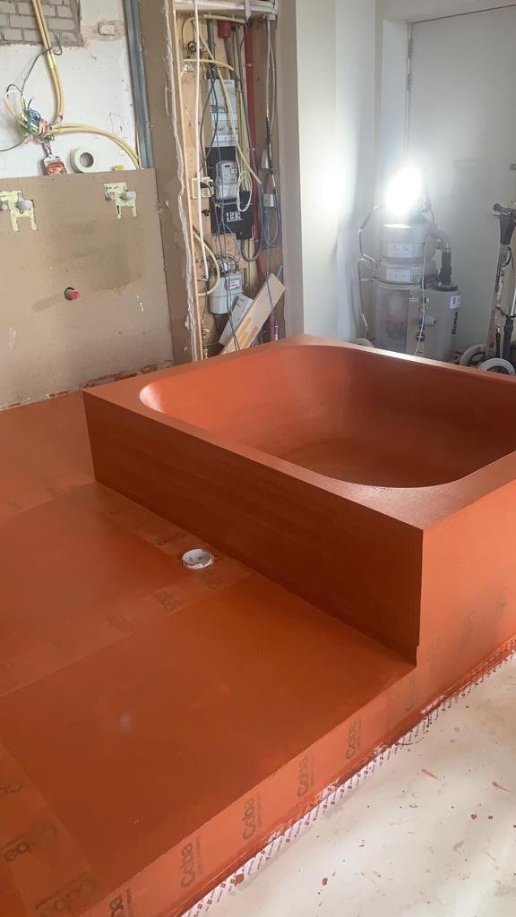 A large, unfinished wooden bathtub installation in a bathroom or construction area.