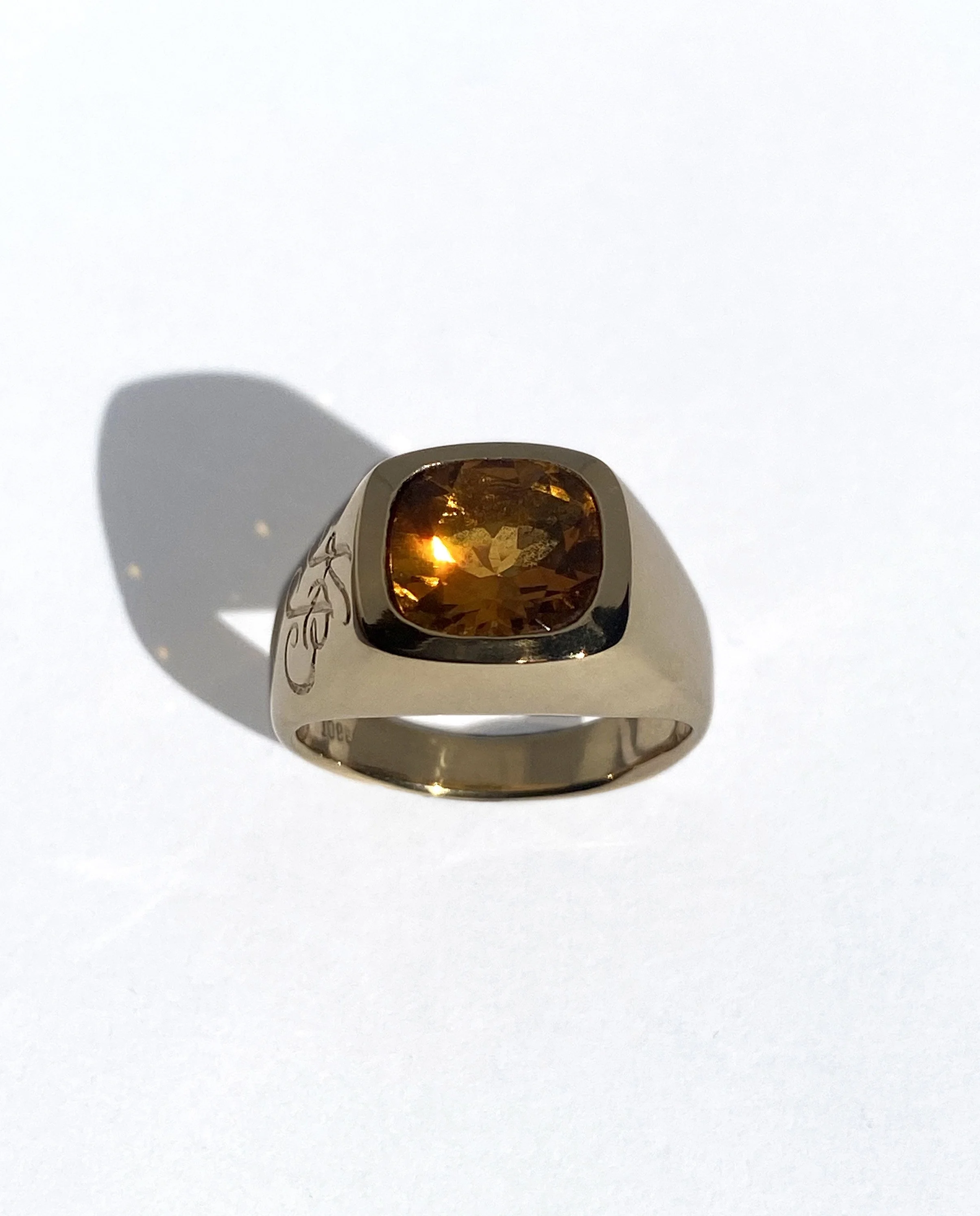 A 18k gold ring with a large amber-colored gemstone in a square setting.