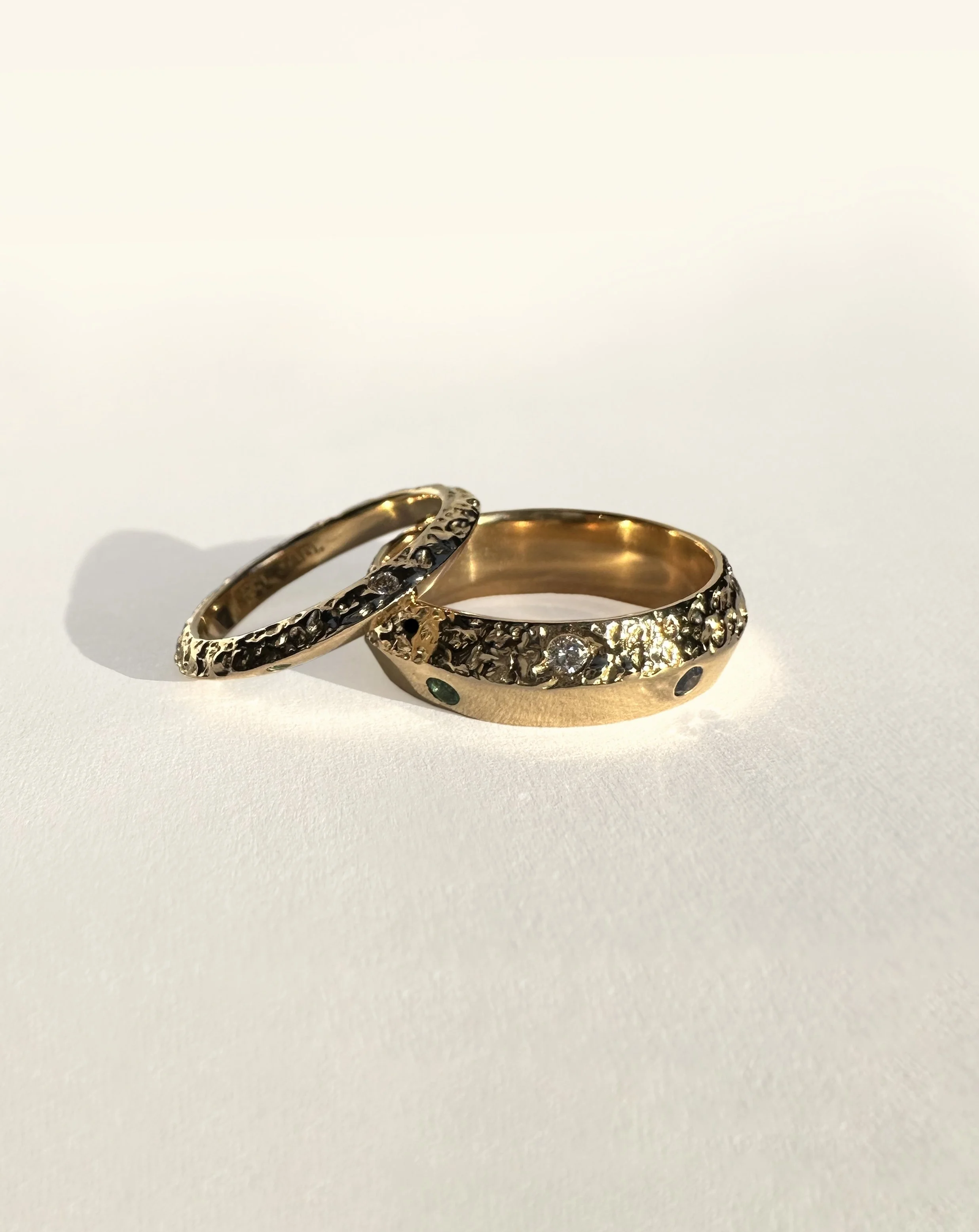 18k wedding bands, contrasting between molten gold and silky smooth. Each ring set with a diamond, emerald and sapphire.