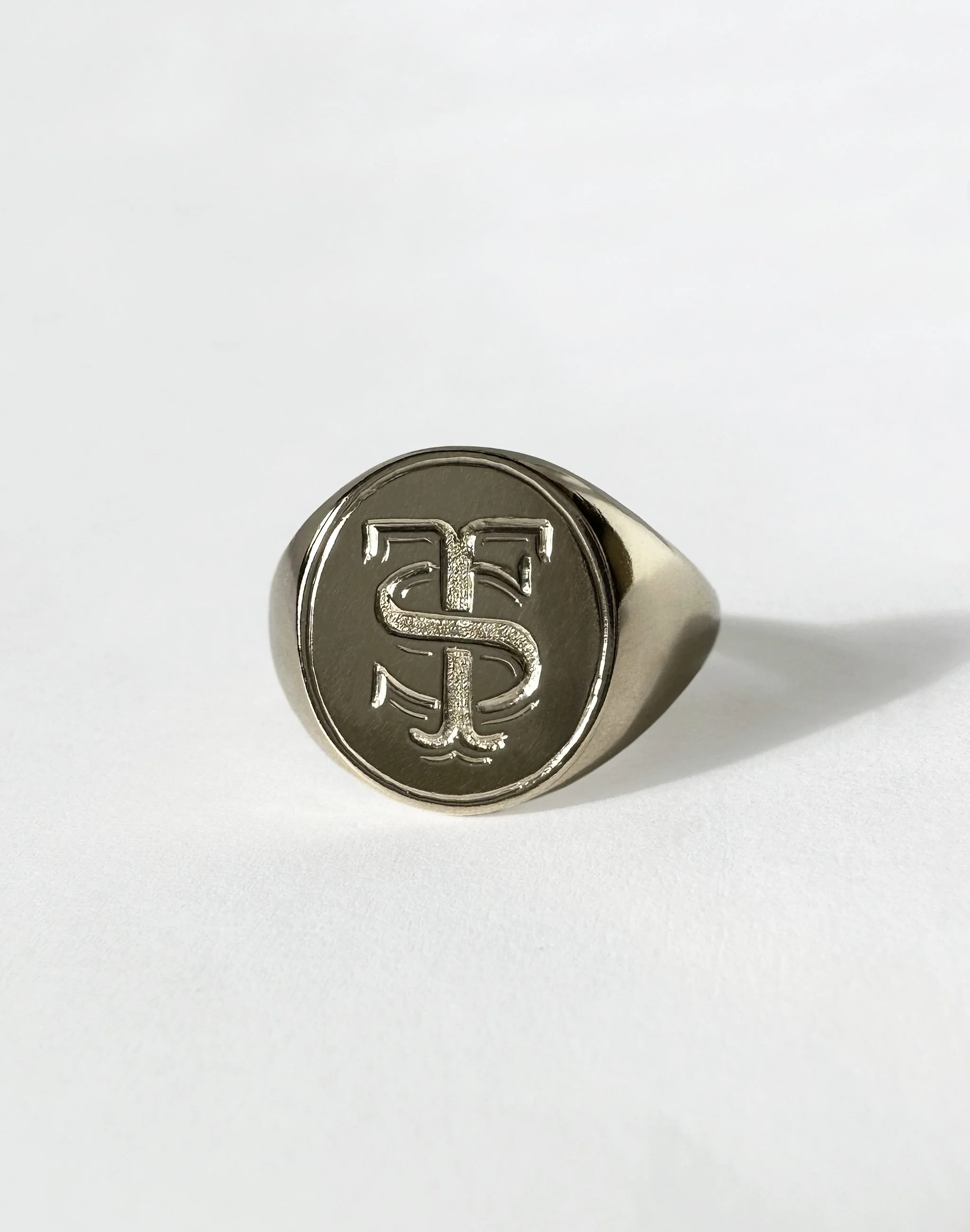 Gold coin-like face featuring an hand engraved 'T' and 'S'