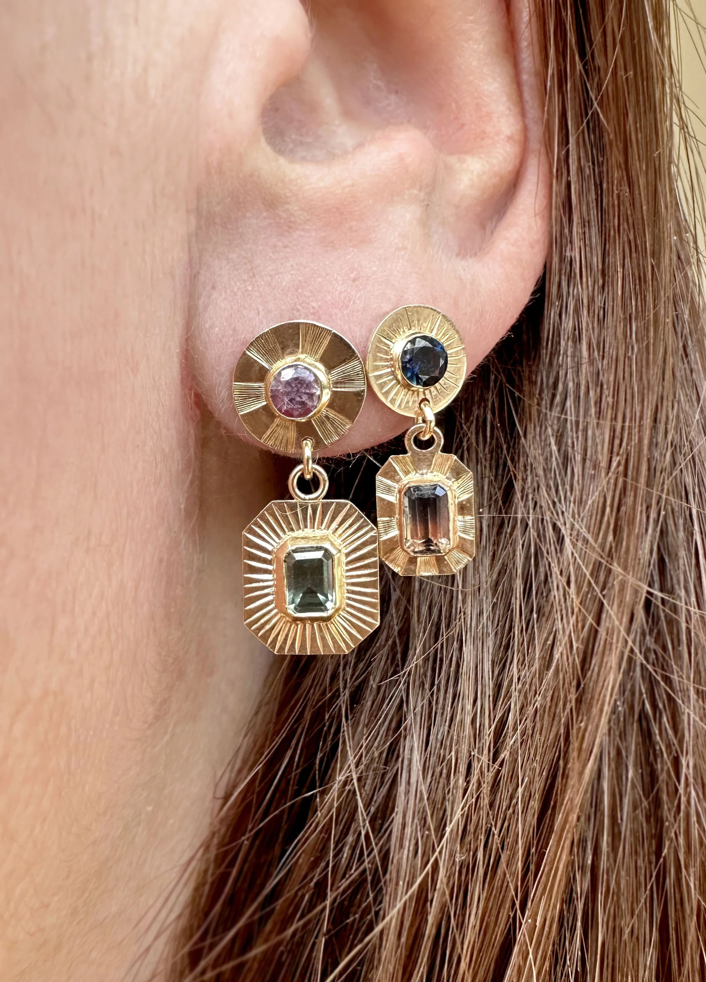 Hand engraved gold earrings with circular and rectangular sapphires.