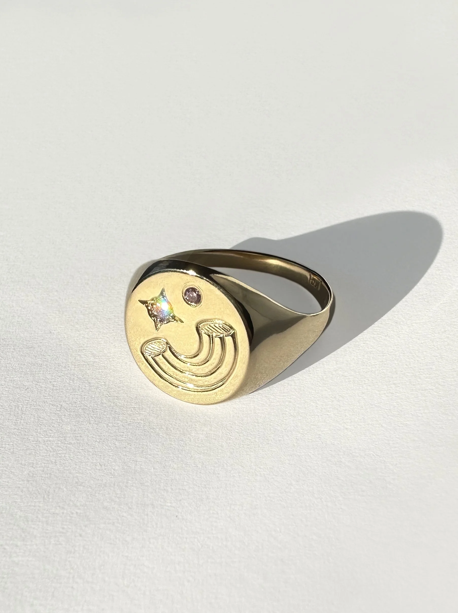An engraved gold ring featuring a piece of pasta with pink and white Argyle diamonds.