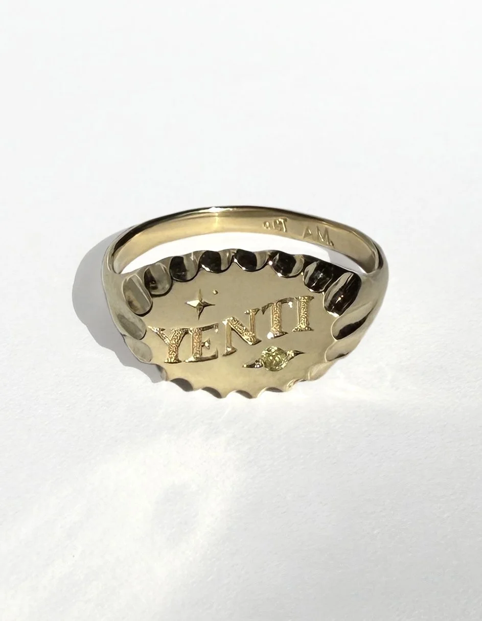 Gold ring with engraved word "YENTI" and star with peridot birthstone.