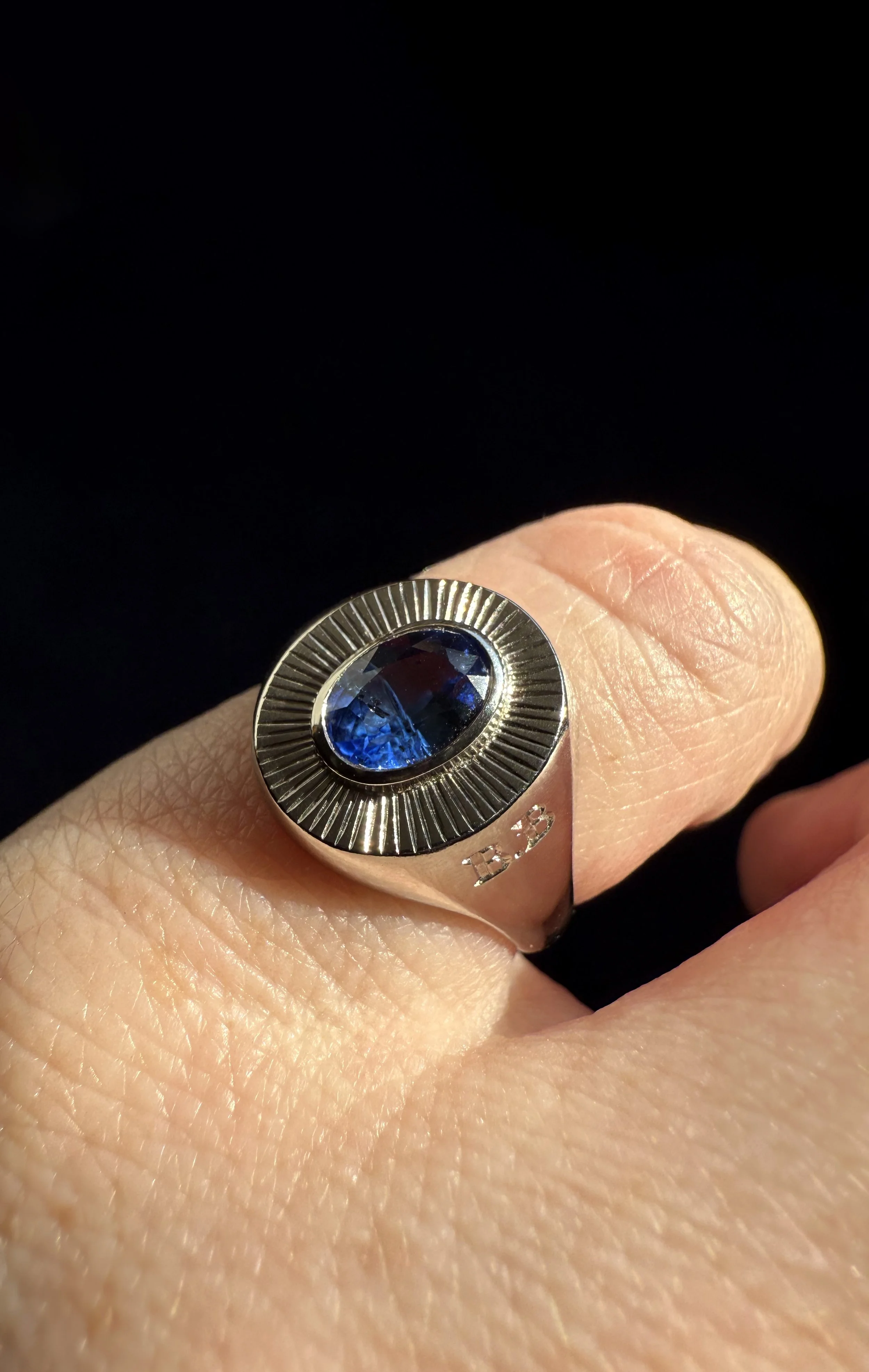 A platinum gold ring with a large Ceylon sapphire with sun ray engraving around the edges.