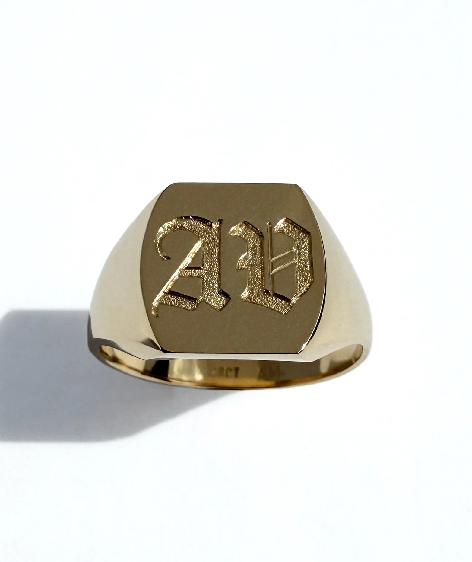 Gold signet ring with engraved Gothic letter 'A' and 'V'.