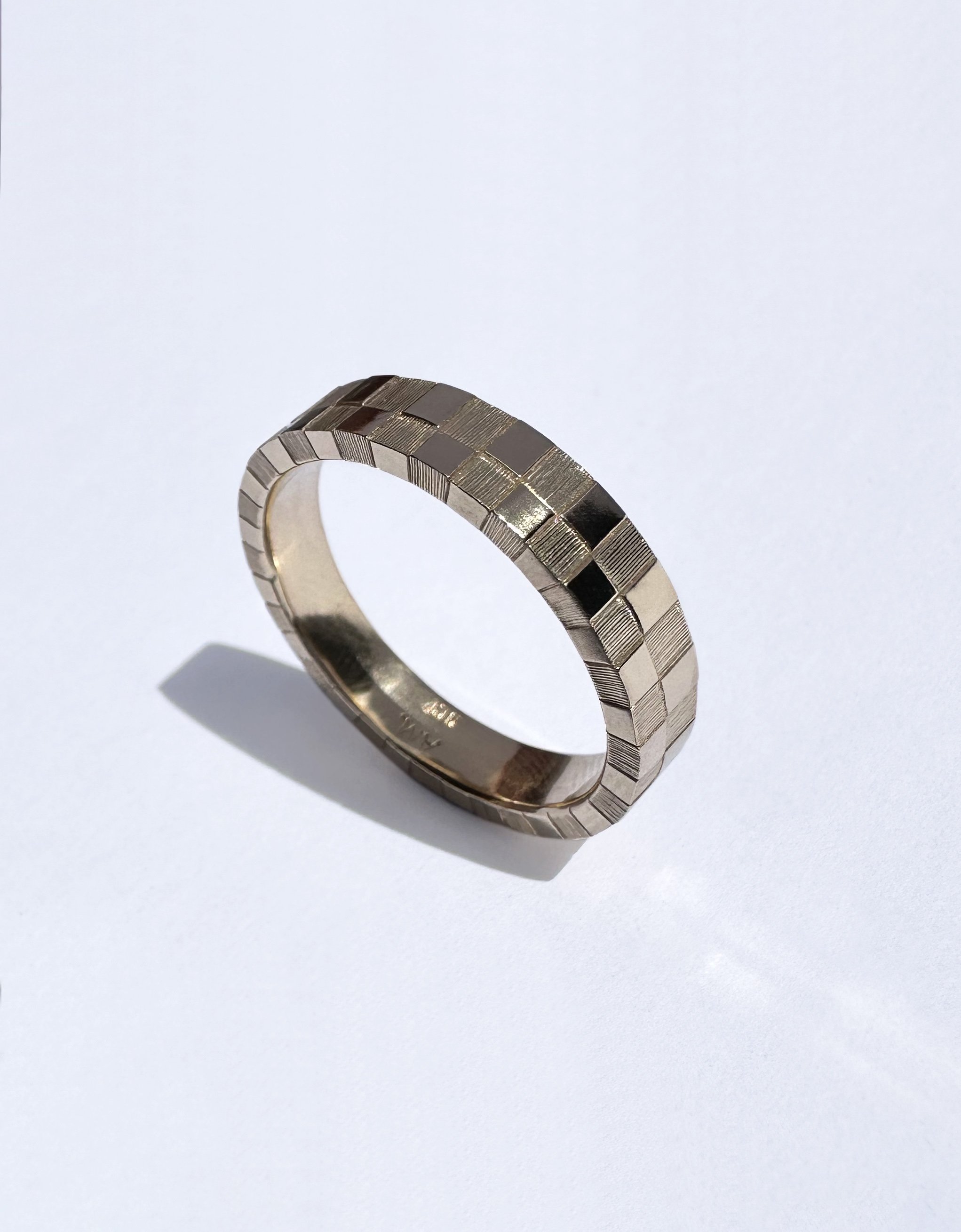 A gold ring with a textured, checkered pattern.