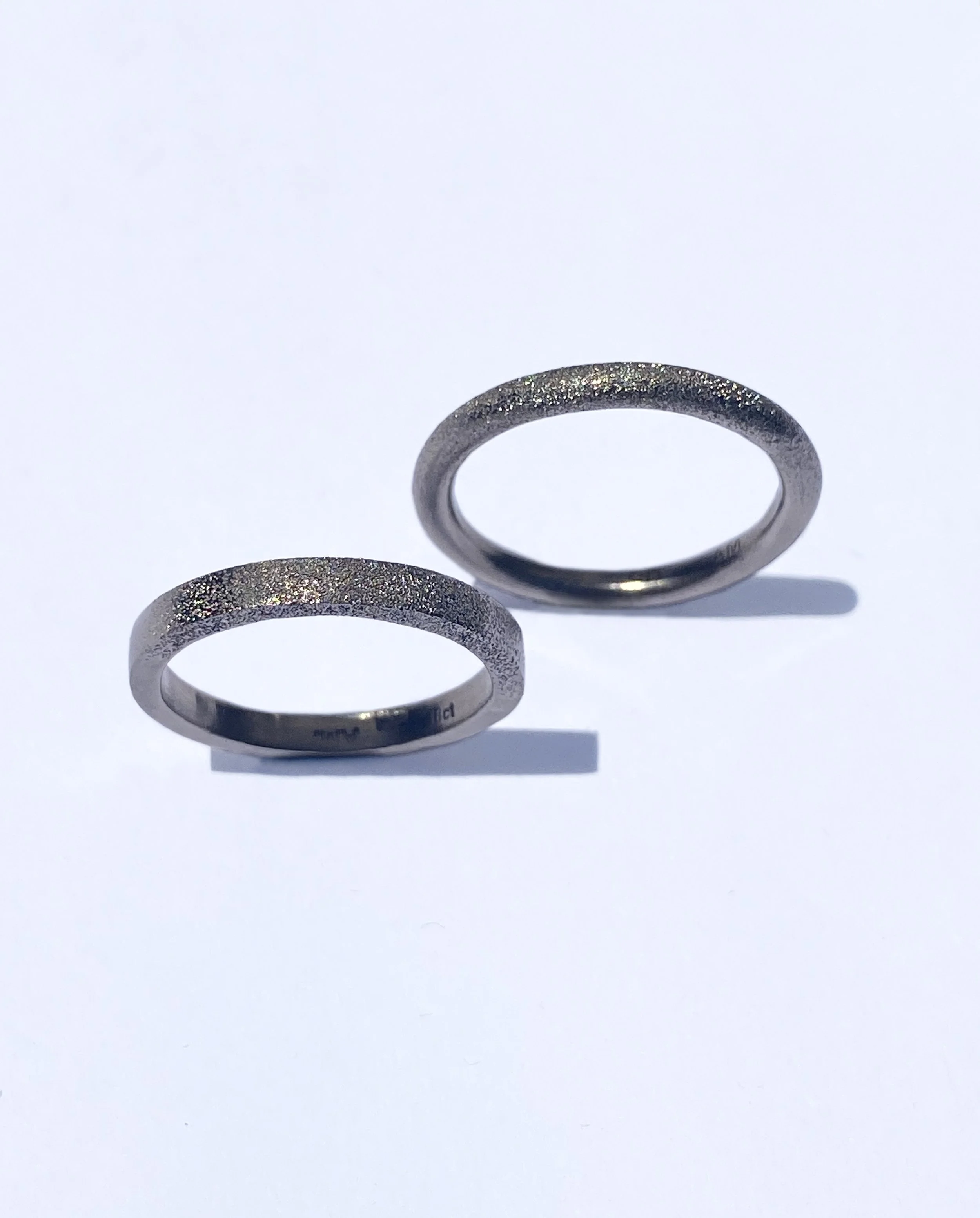 Two white gold rings with a hand hammered textured surface.