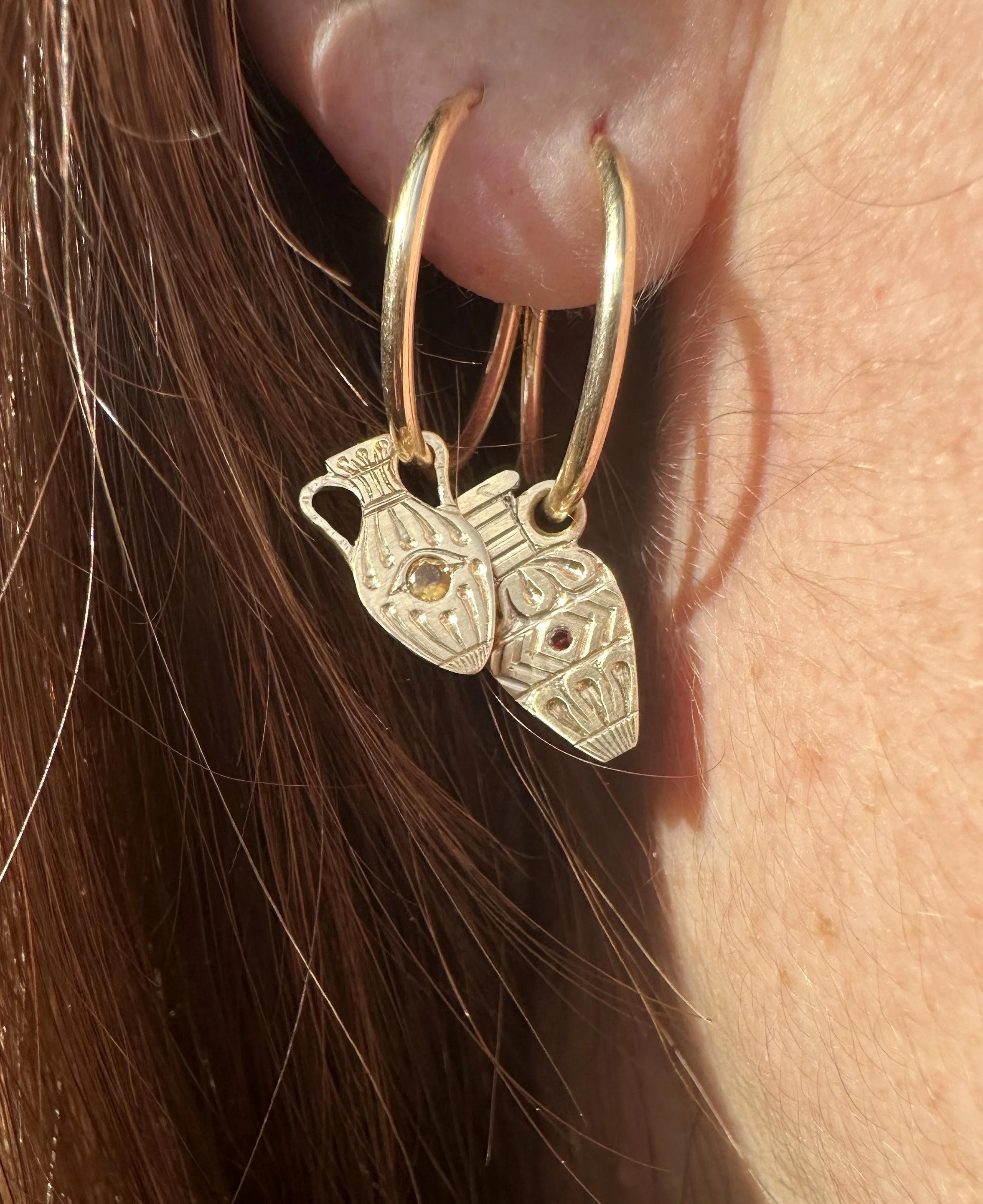 Engraved gold earrings in the shape of an urn. Featuring coloured stones in the centre in the urns.