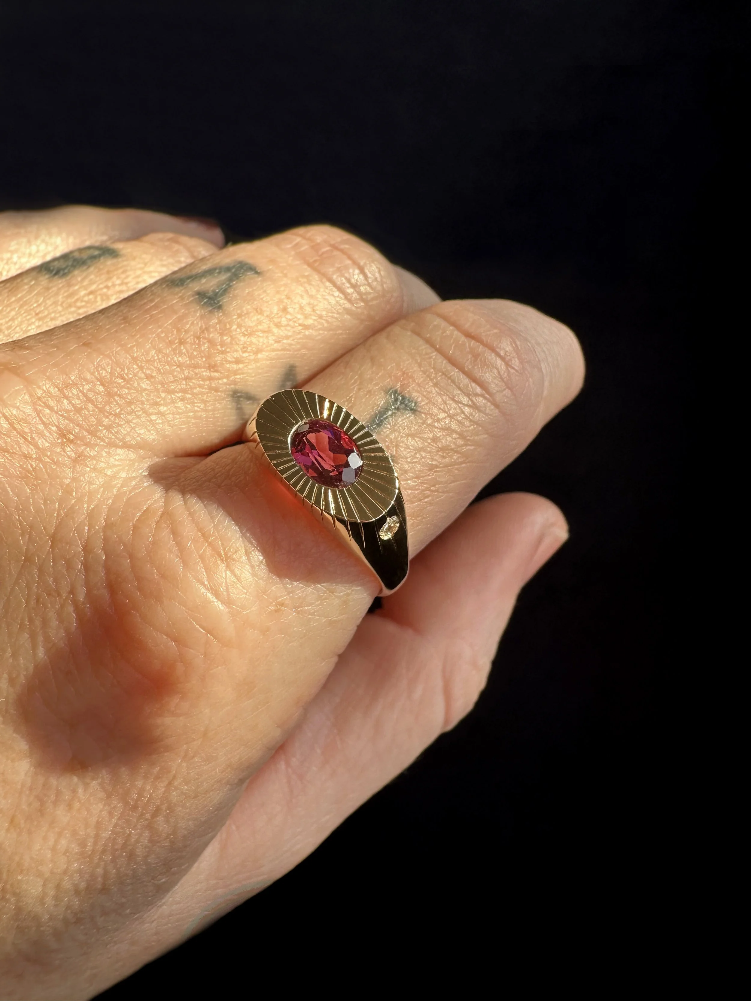A gold ring with a red gemstone.