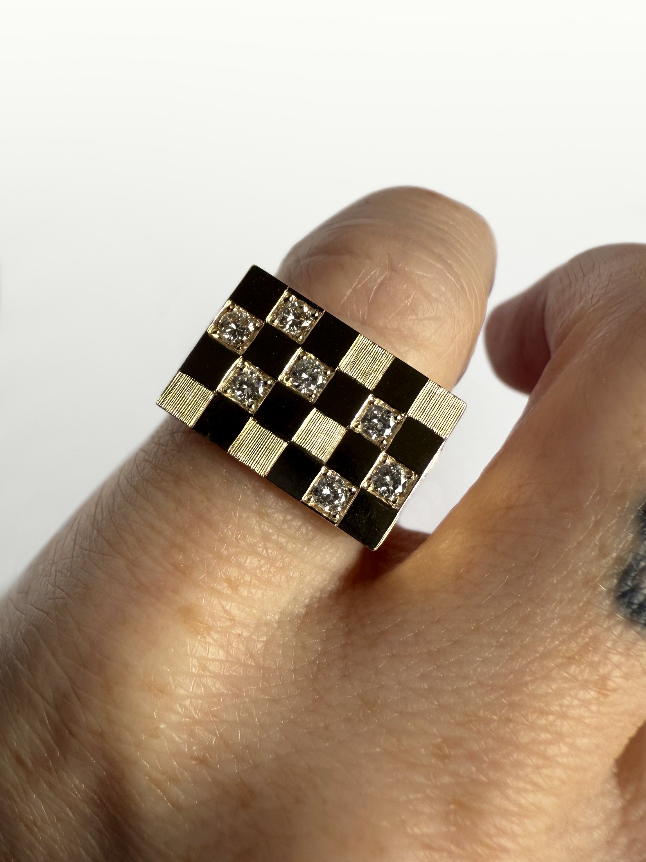 A yellow gold ring, engraved with a checkerboard pattern featuring heirloom embedded diamonds.