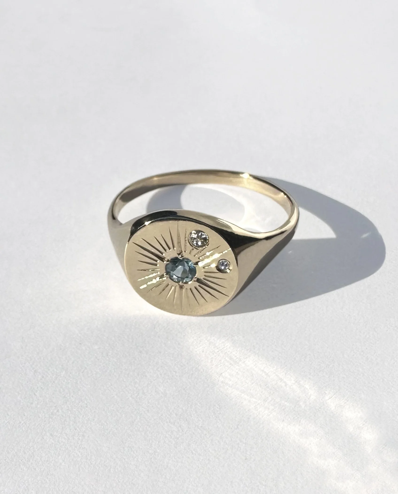 A 9k gold ring with an Aquamarine stone centre, small embedded diamonds and engraving around the centre stone