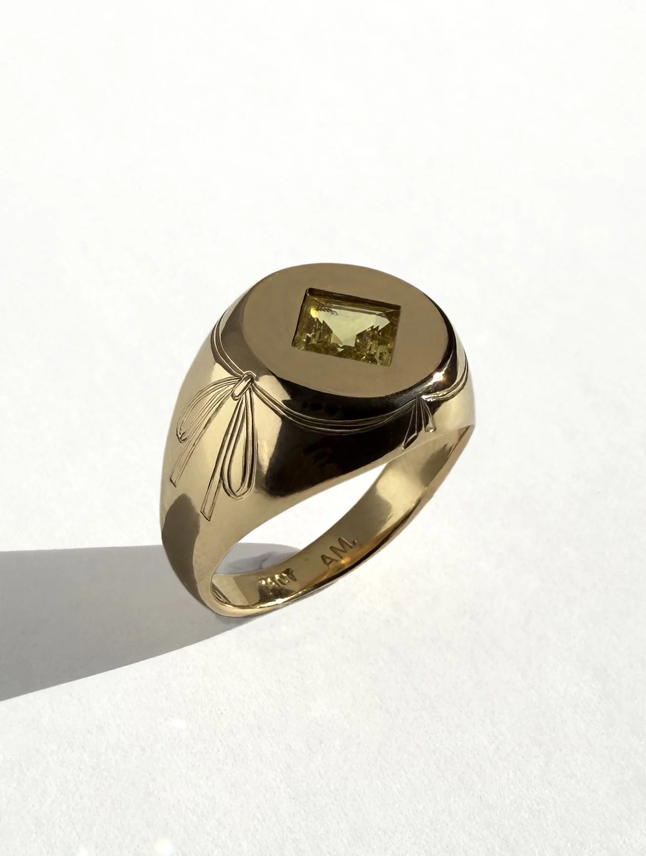 The Teatro ring in luscious 18ct gold, set with the Carré cut sapphire. Hand engraved bows on the band of the ring. 