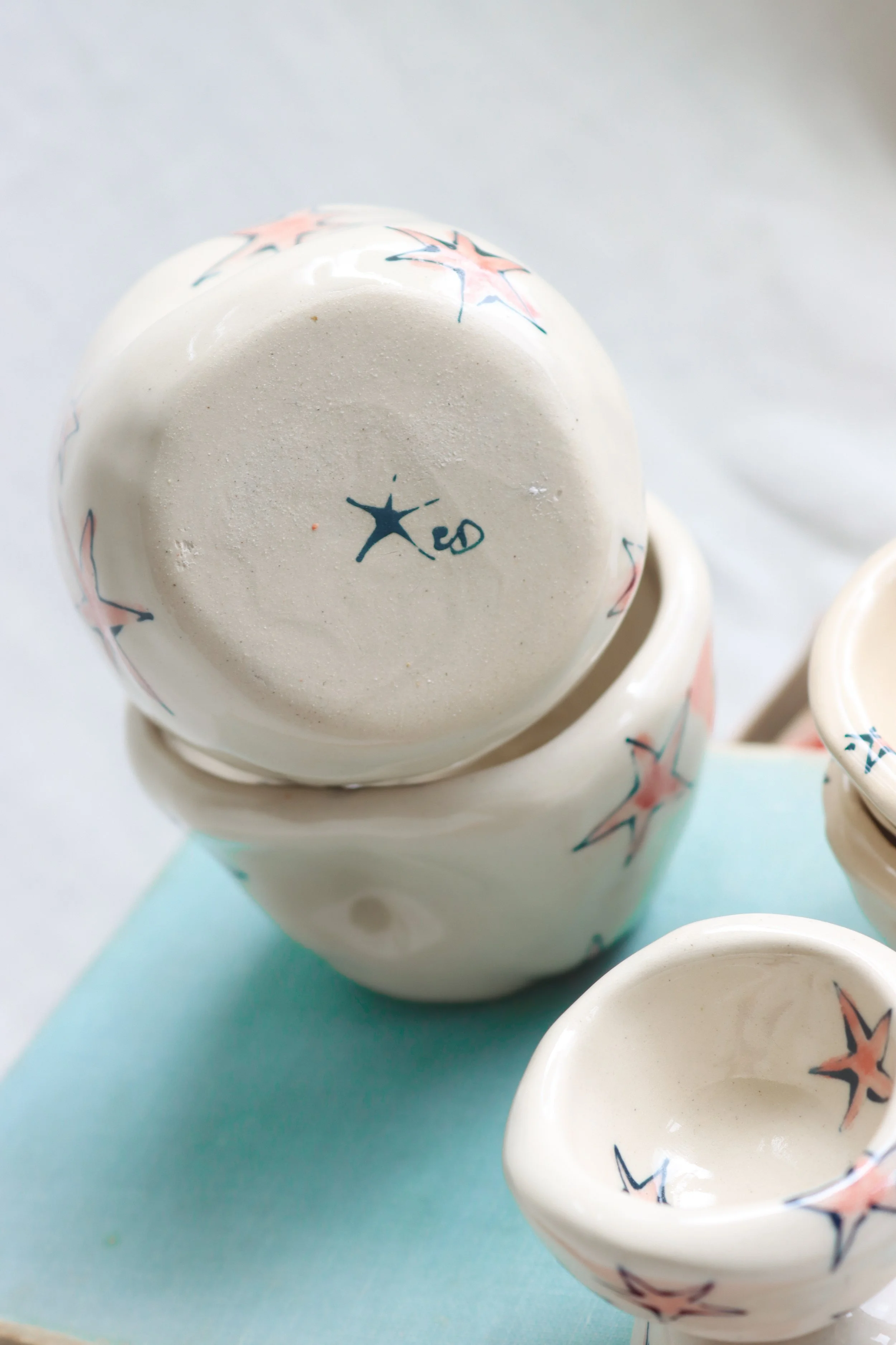 Two white ceramic cups stacked. Each one is covered with red stars with blue outlines.