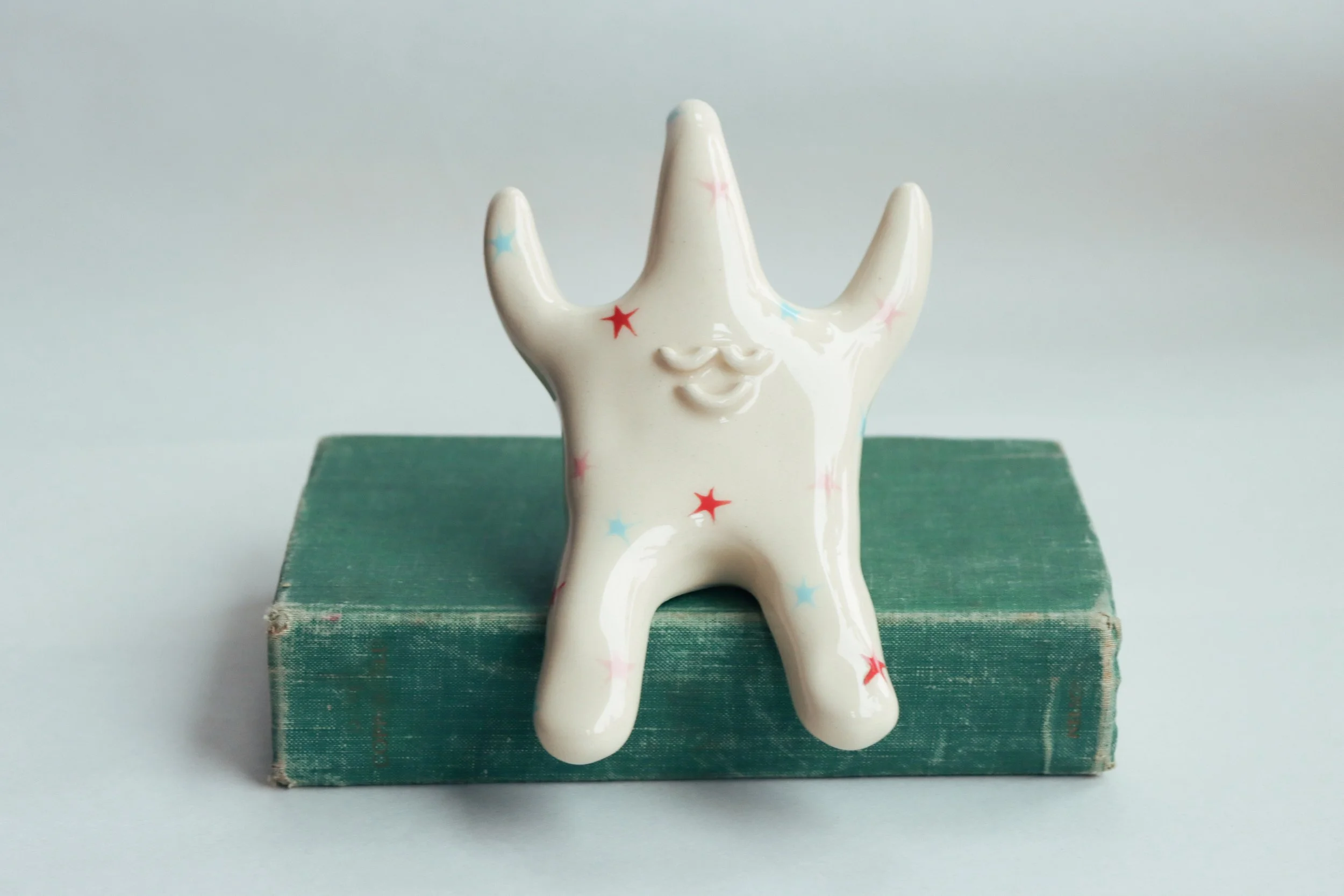 Ring holder in the shape of a star. It is decorated in red, pink, and blue stars.