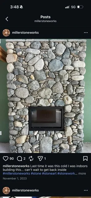 A wall decorated with smooth river stones surrounding a mounted flat-screen TV.