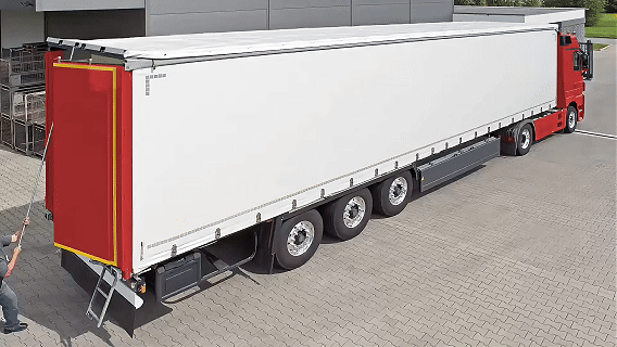 A large commercial semi-truck with a white cargo trailer and red cab parked on a paved surface.