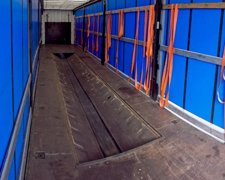 Empty aircraft cargo hold with blue walls and orange safety straps.