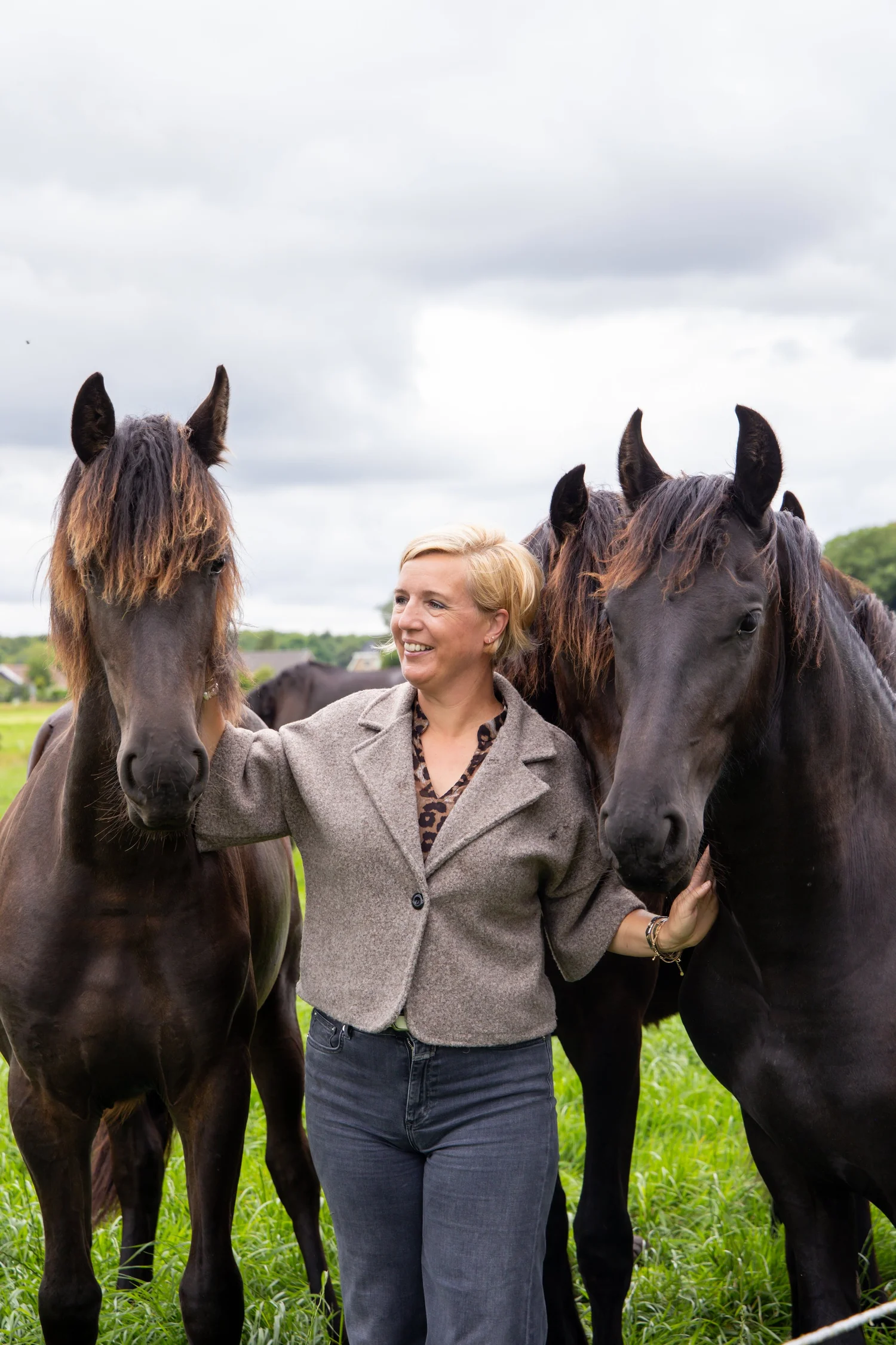 Rianne Sibma tussen haar losse Friese paarden in het weiland