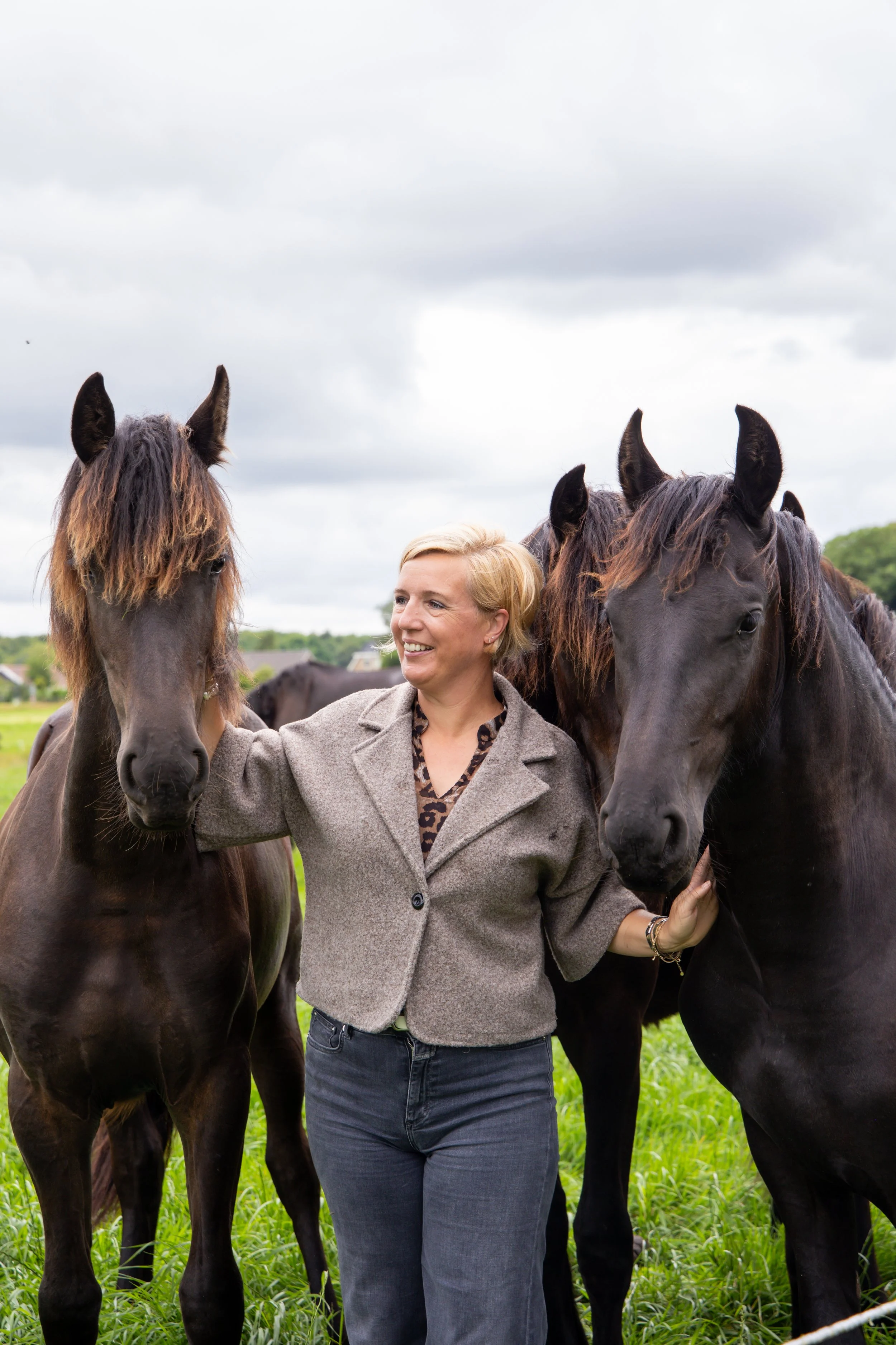 Rianne Sibma tussen haar losse Friese paarden in het weiland in Rottum