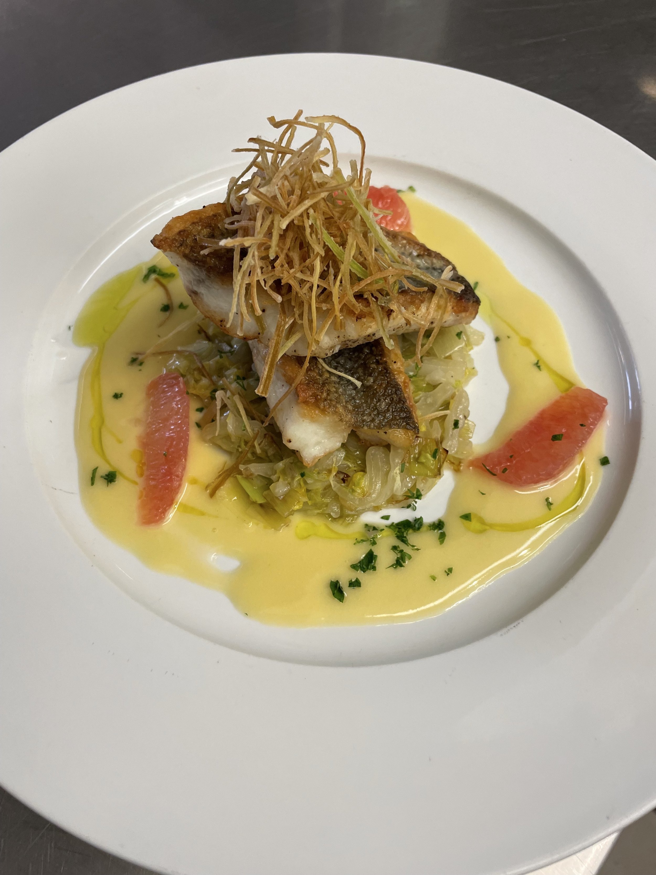 Pan Seared Sea Bass over Cabbage with Grapefruit Beurre Blanc, and Crispy Leeks to top