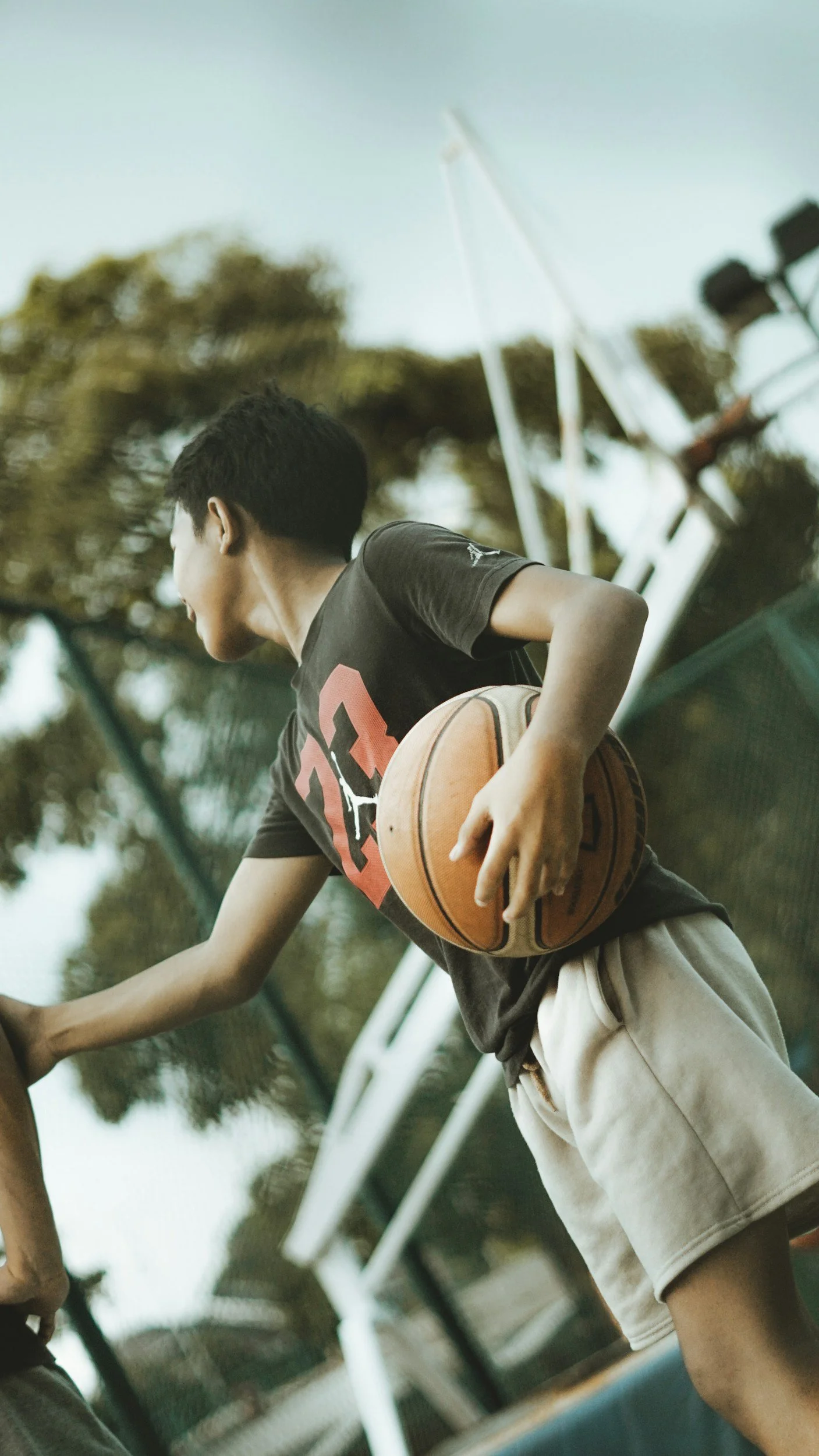 A young boy holding a basketball on an outdoor basketball court.